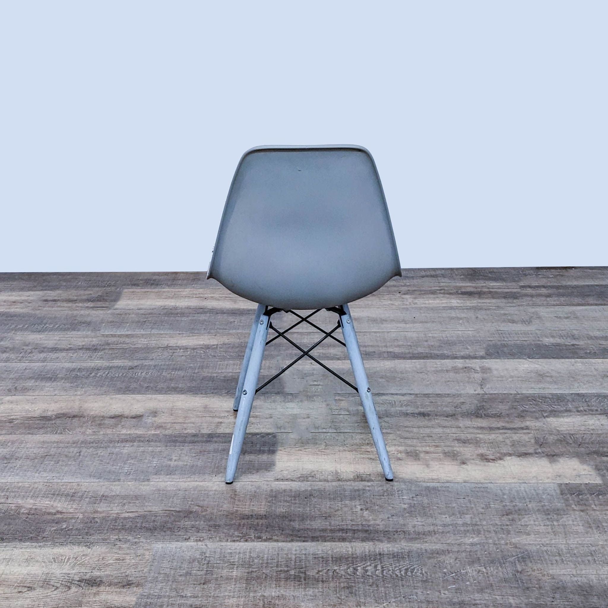 Reperch brand dining chair with a contoured two-toned plastic seat and wooden legs with a metal Eiffel base on a wooden floor.