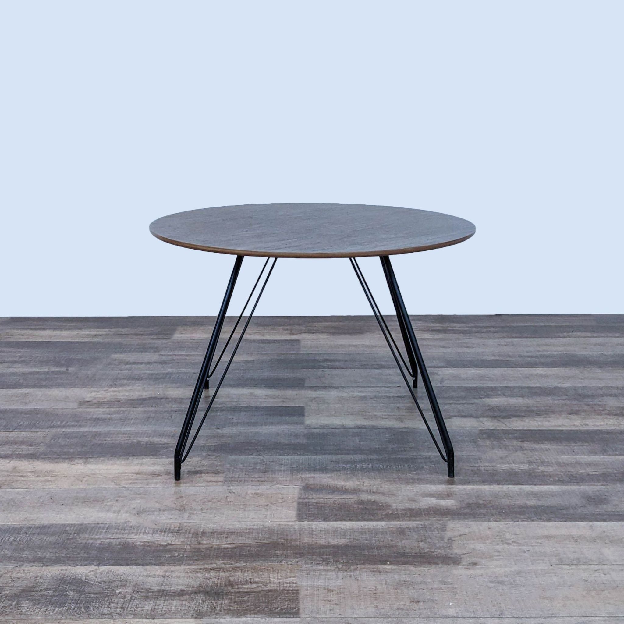 1. Round Satellite dining table by Modway with a wood grain veneer MDF top and black steel hairpin legs on a wooden floor.