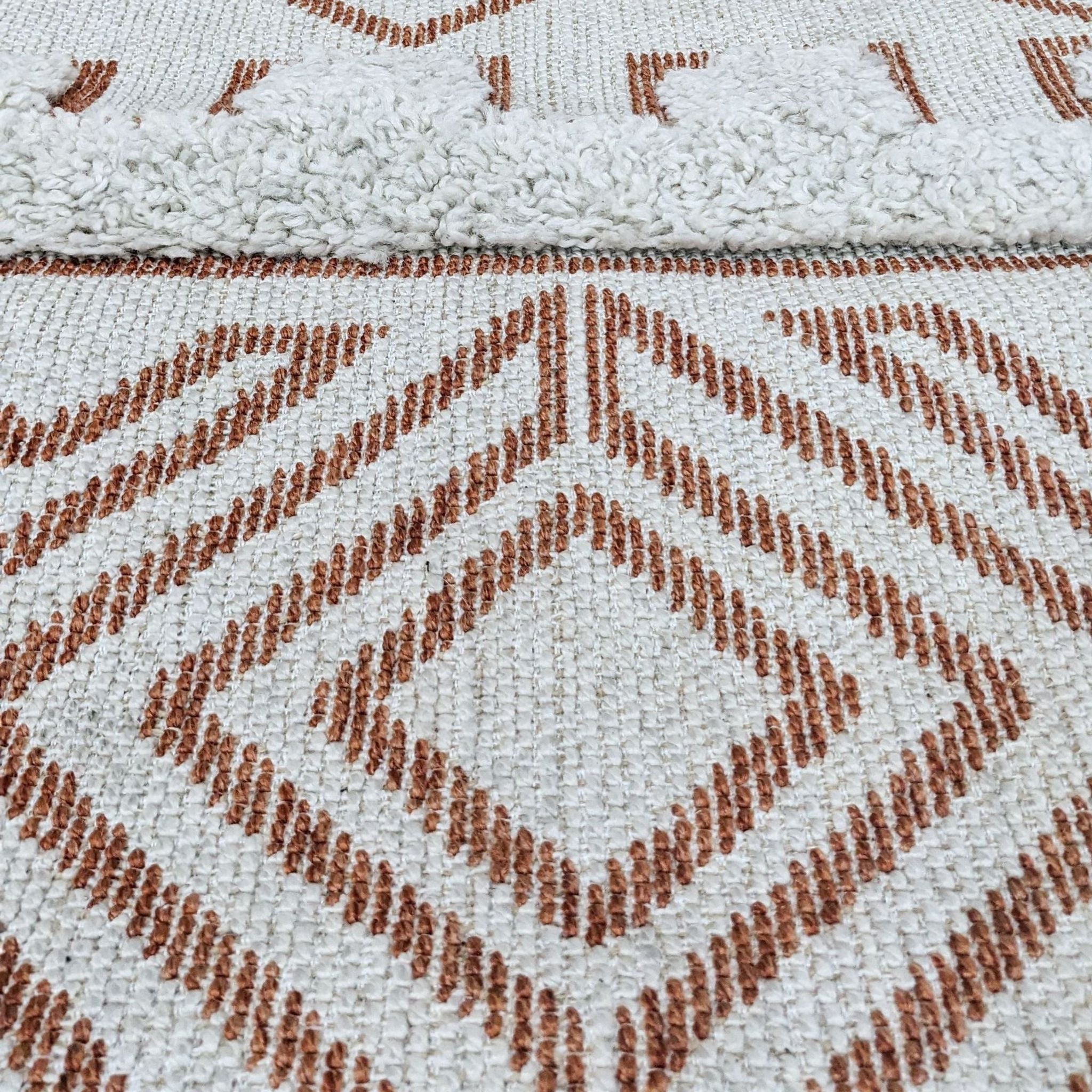 NuLoom Altos area rug displaying a tribal print in brown on a textured white high-low weave with braided tassels.