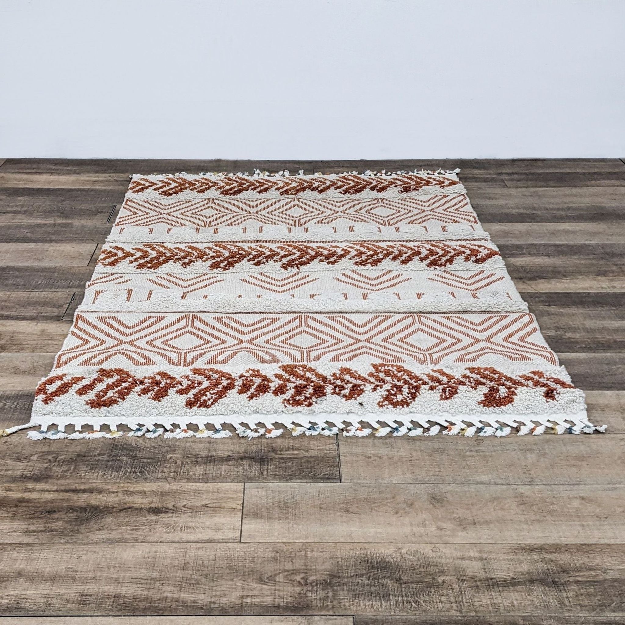 Alt text 1: nuLOOM's Altos area rug displayed on a wooden floor, showcasing a tribal pattern with tassels on the ends.