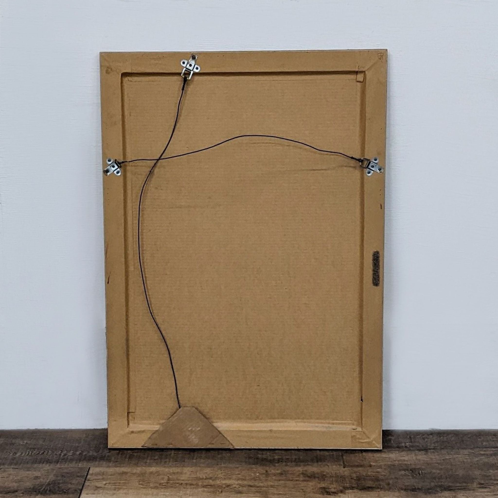 Back view of a Reperch wall mirror showing cardboard backing and hanging wire.