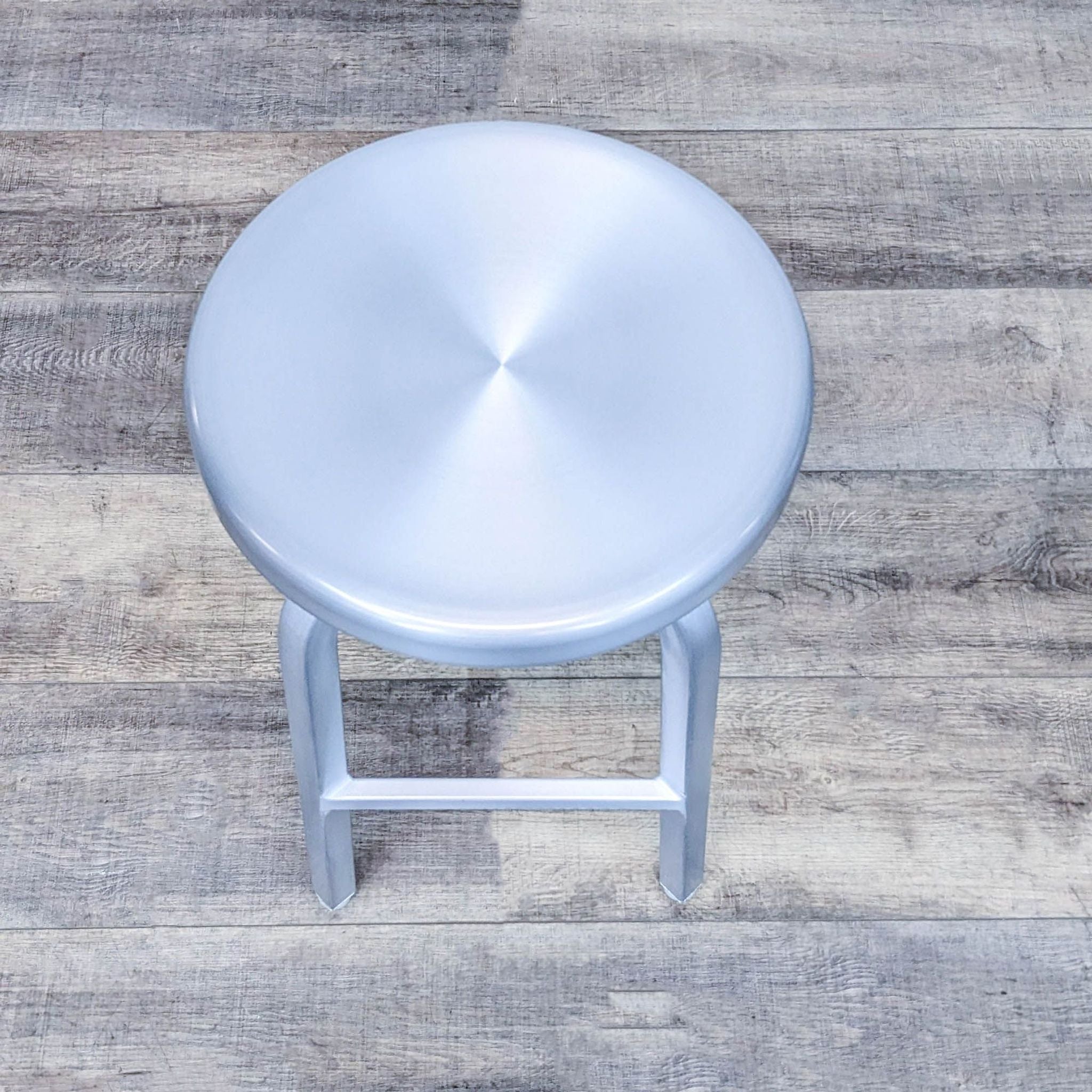 Reperch metal stool featuring a swivel seat with a sleek industrial look, against a wooden textured floor.