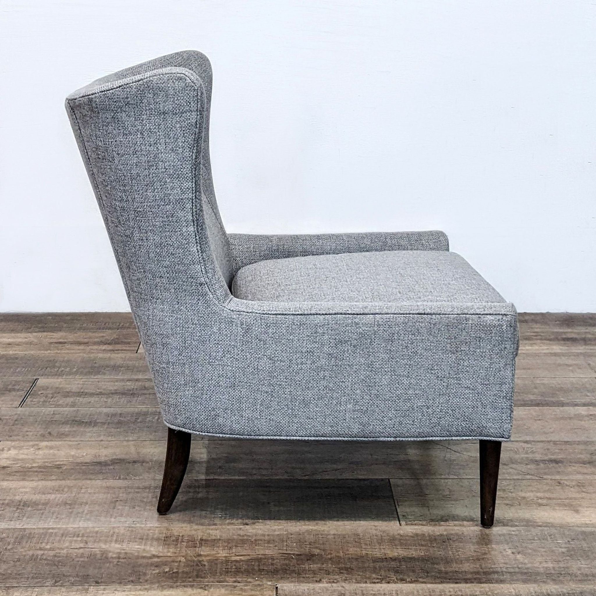Side view of Four Hands' Marlow chair, displaying the contemporary wing chair silhouette and elegant wood legs in a lounge setting.
