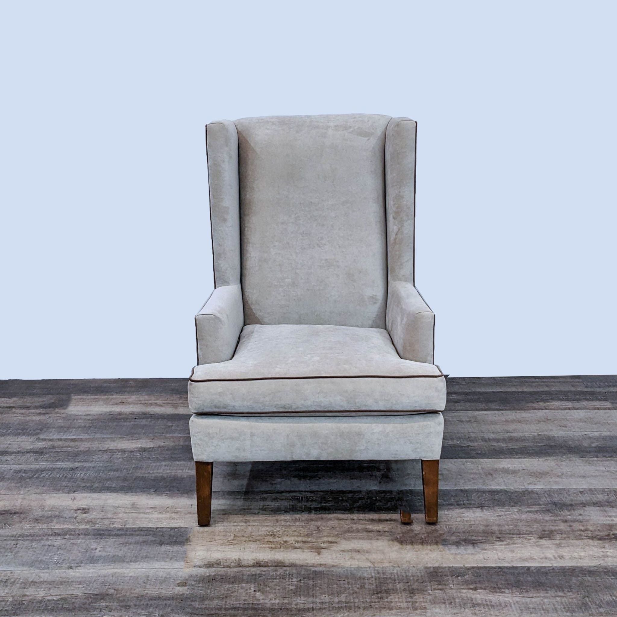 Reperch contemporary wingback chair in a front view, with soft upholstery, contrasting trim, and tapered legs.