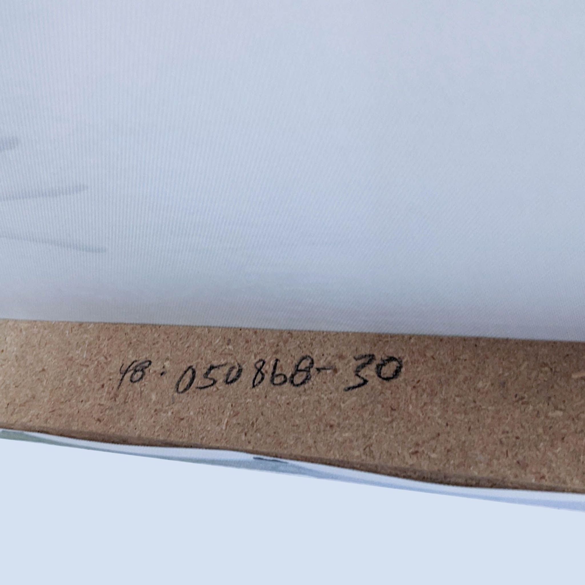 Close-up of a handwritten code on the back of a canvas print by Reperch with soft blue tones, likely indicating edition or inventory number.