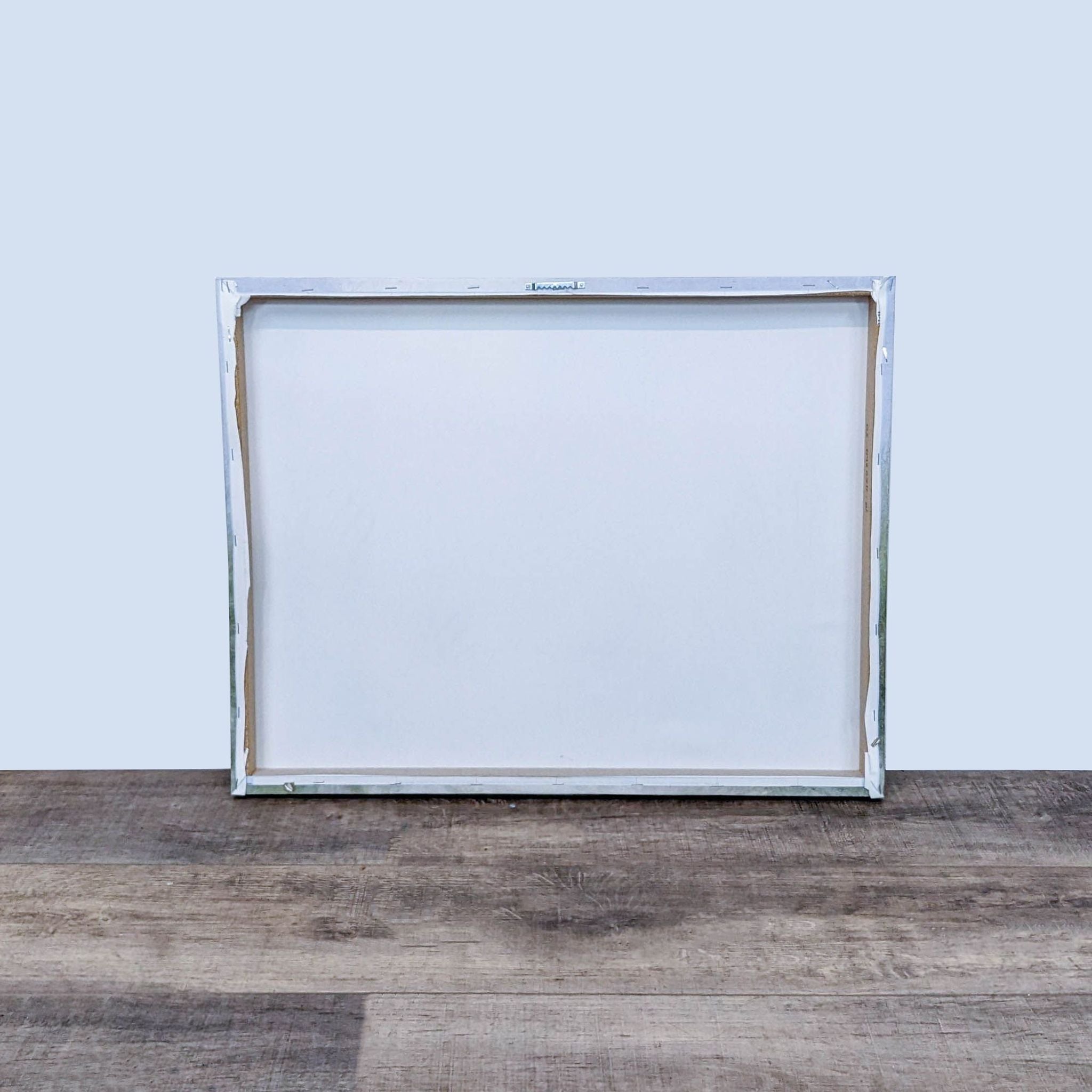 Alt text 2: Back view of a Reperch-branded canvas frame, displaying a blank white canvas and a sticker with product numbers, on a wooden surface.