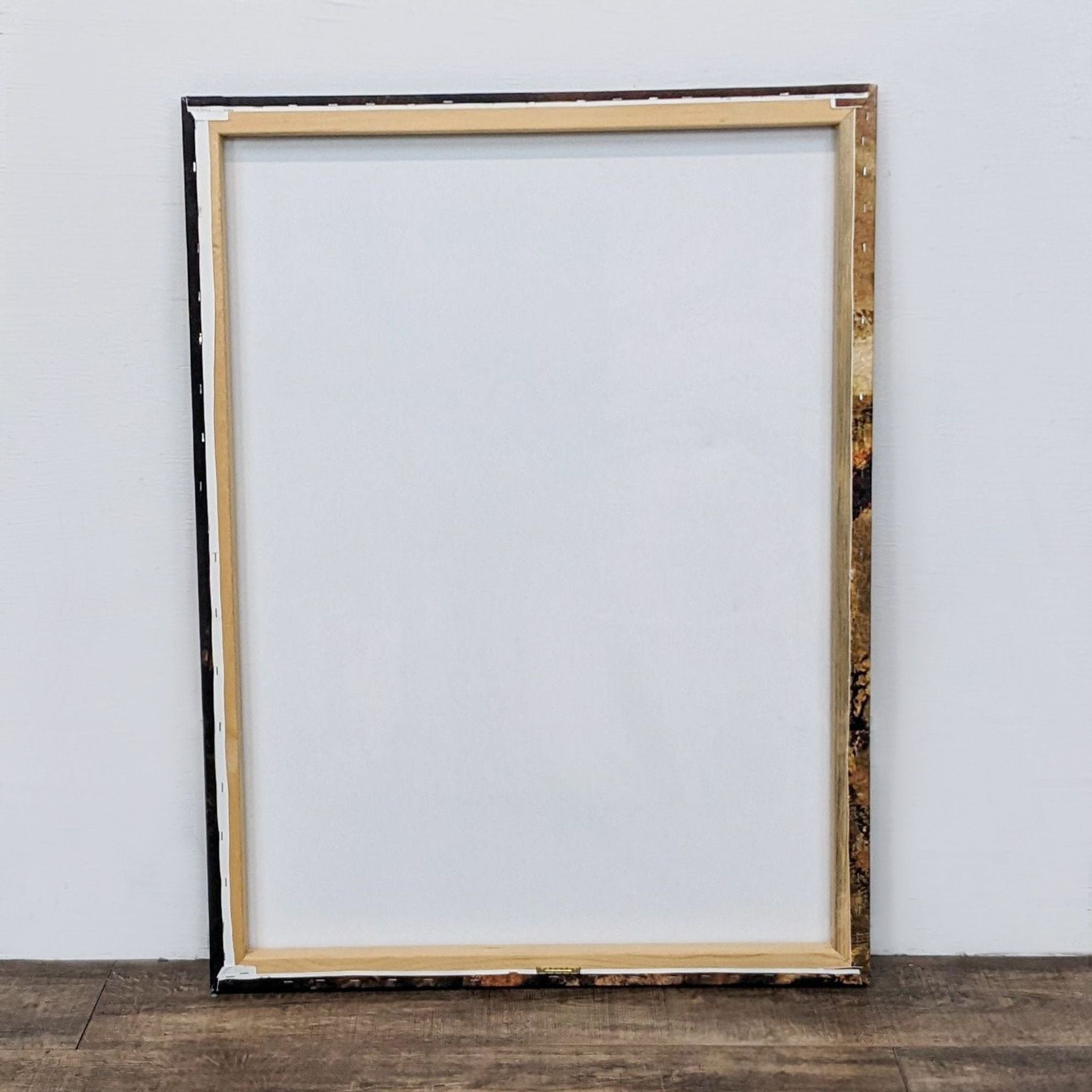 Back view of a Reperch canvas print showing the wooden frame and blank reverse side, standing against a white wall.
