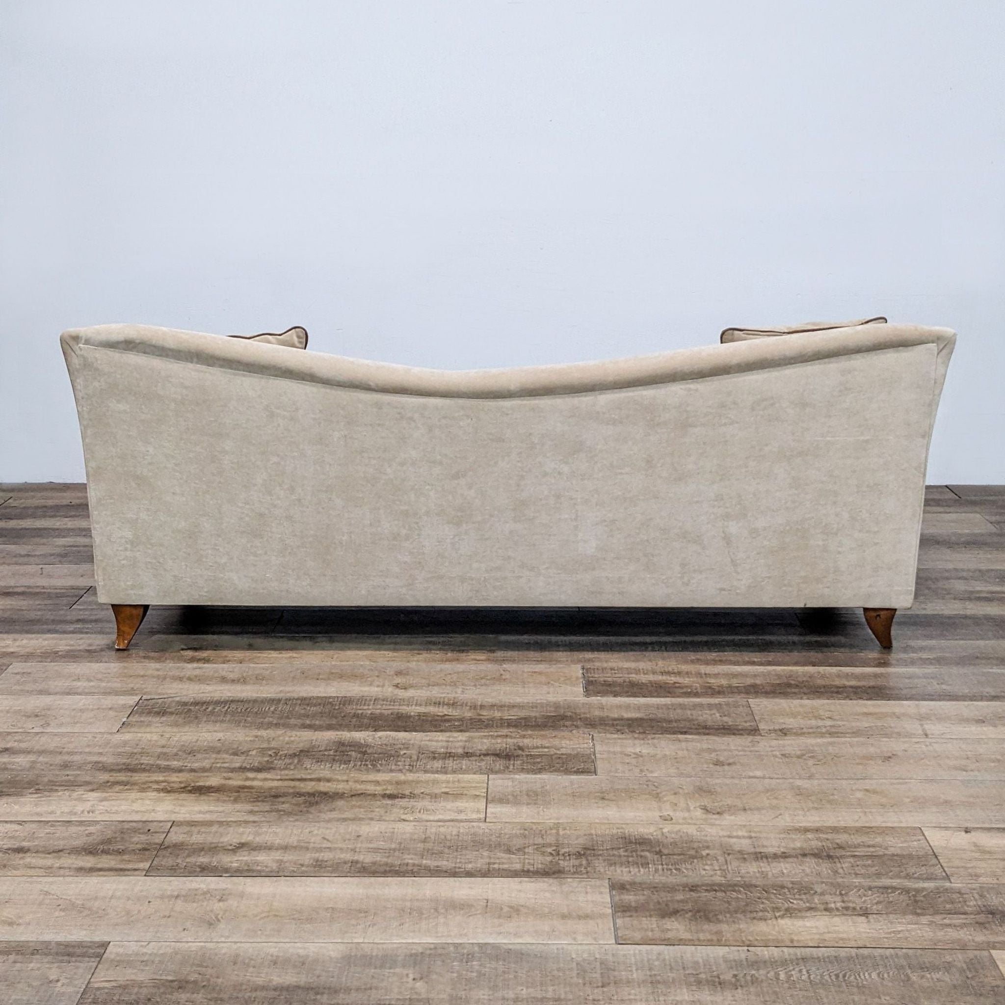 Rear view of a Reperch 3-seat fabric sofa showing its curved back and wooden feet on a wooden floor.