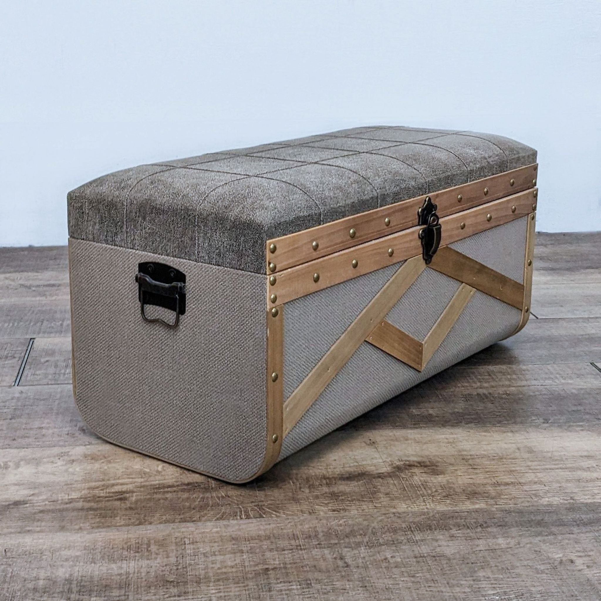 Reperch fabric trunk with wood detailing, brass studs, and dark metal hardware, used as a stool or bench.