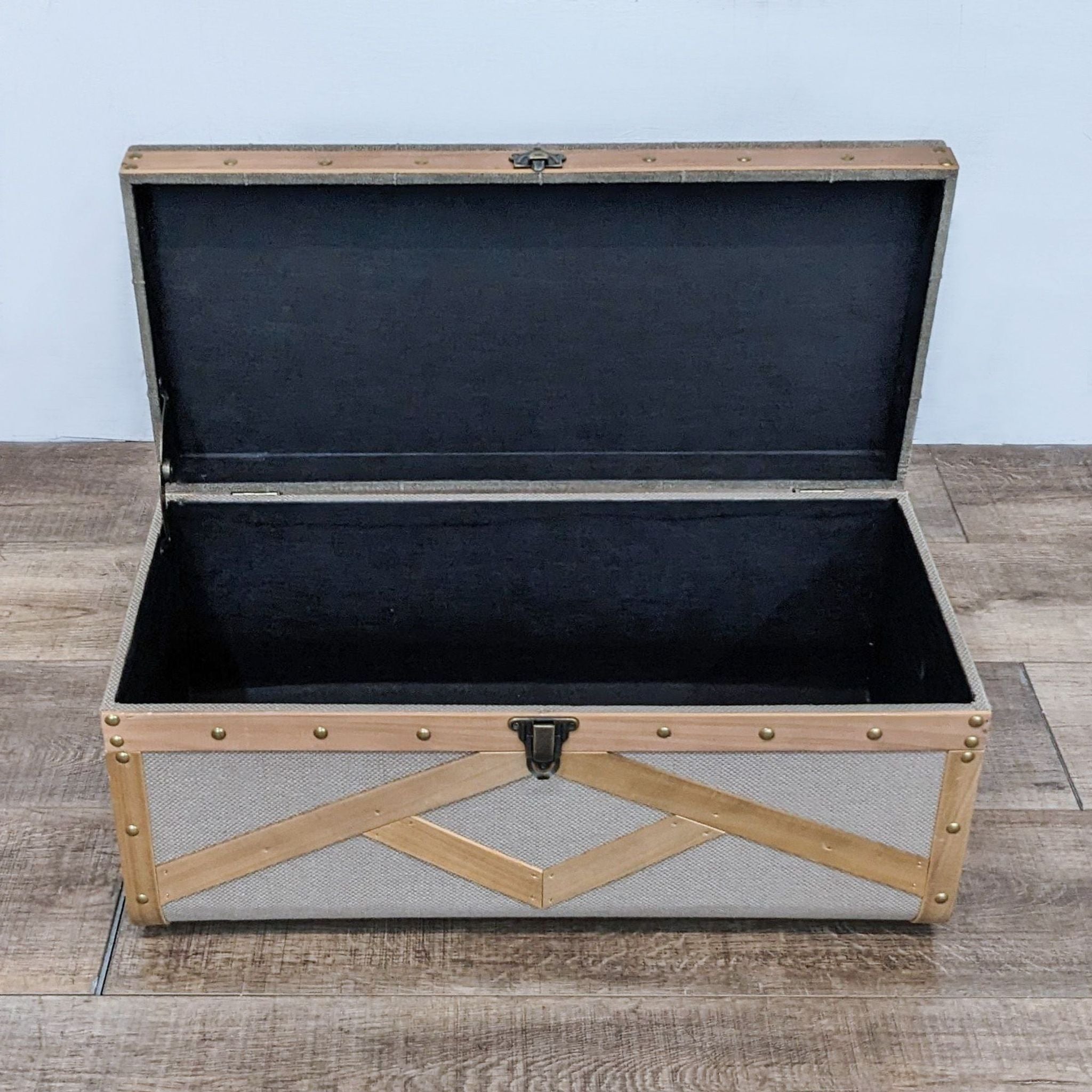 Open Reperch fabric storage trunk showing black interior, with brass and wood detailing.