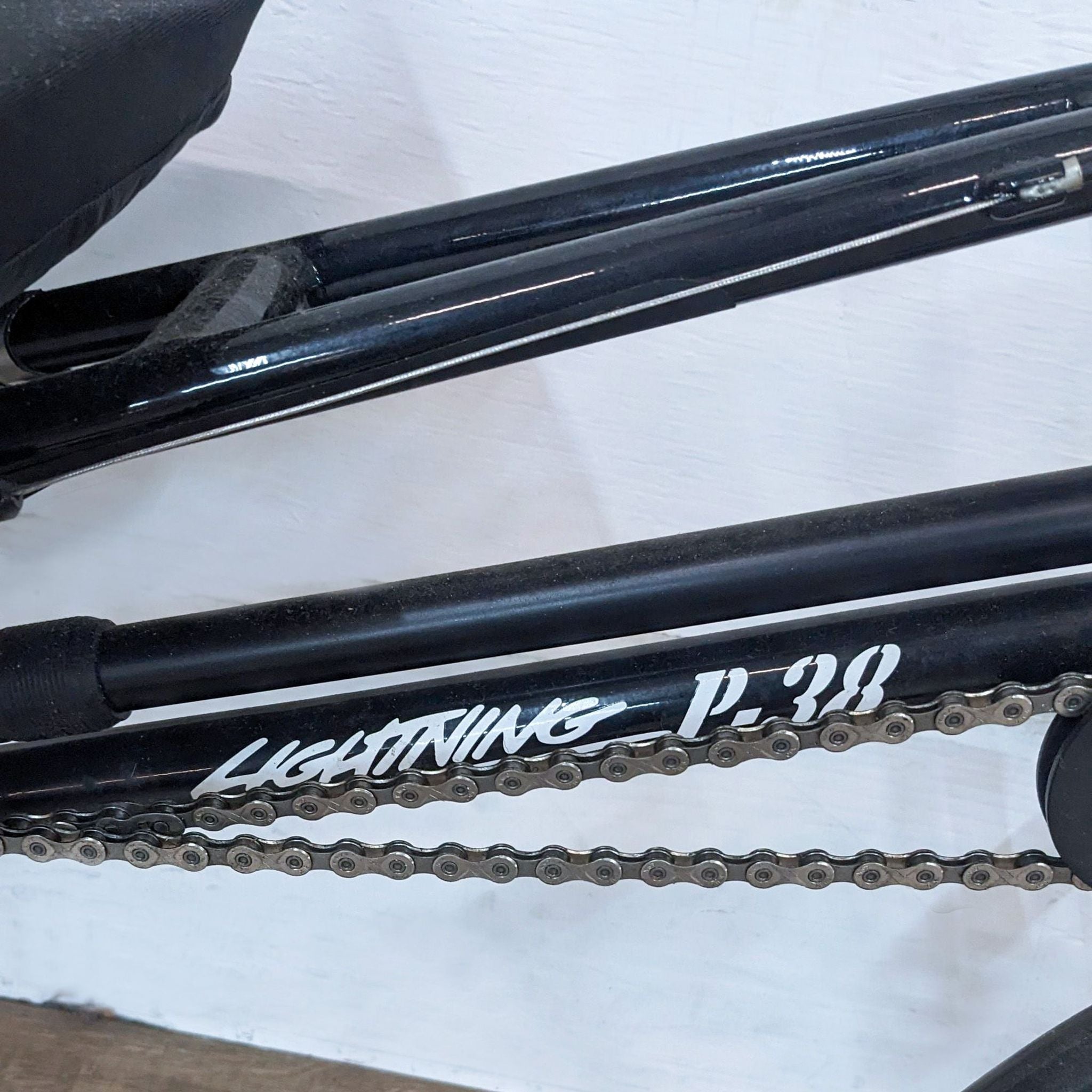 Alt text: Close-up of a black Lightning P-38 bicycle frame with visible bike chain and brand logo.
