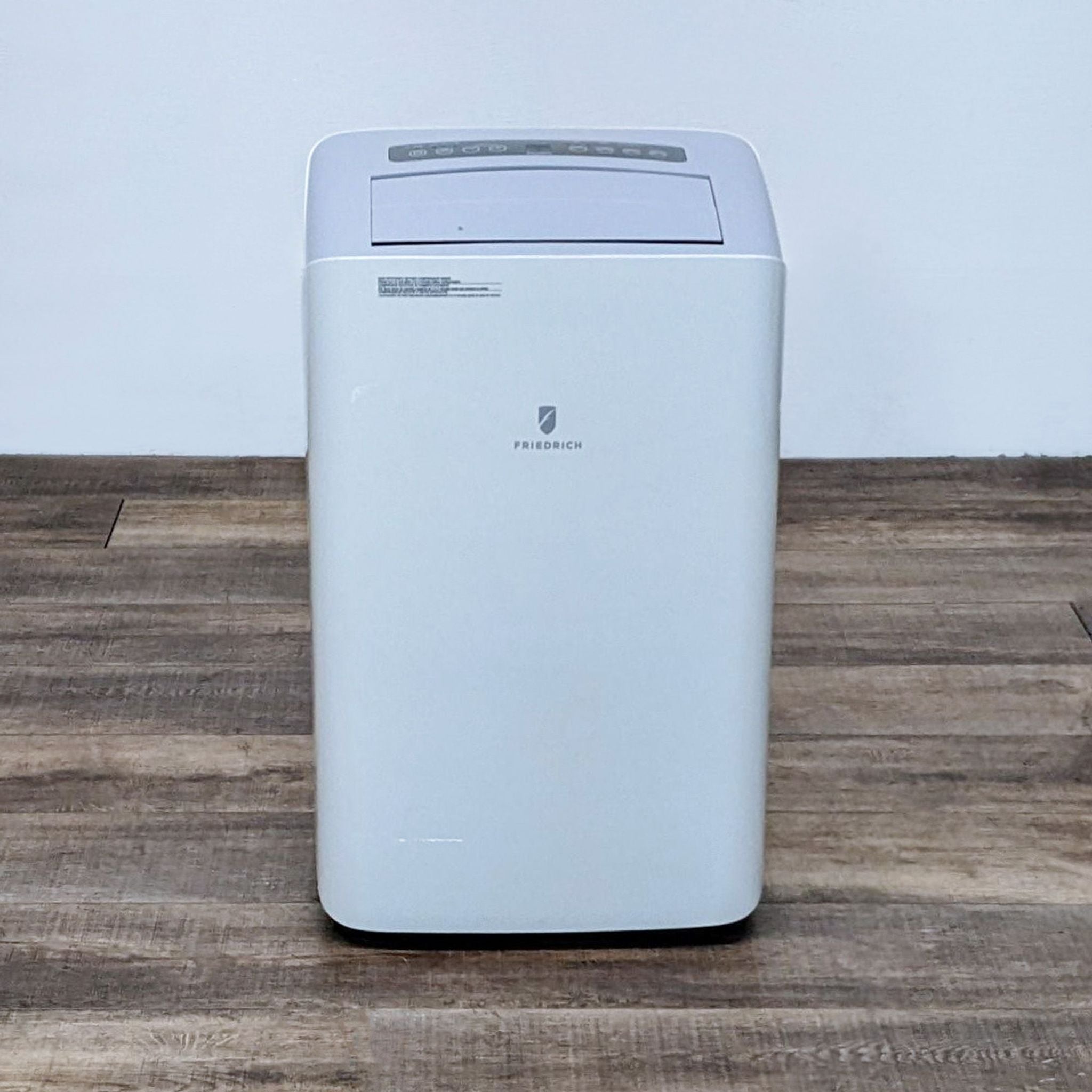 Alt text 1: Front view of a Friedrich portable air conditioner in a room with wooden flooring.