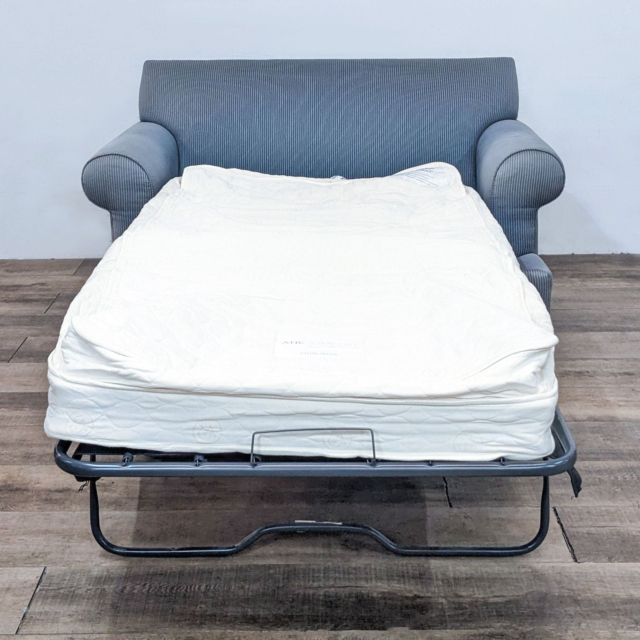 Inflatable twin mattress extended from an Ethan Allen sleeper loveseat sofa with a label showcasing the Air Comfort Sleep System.
