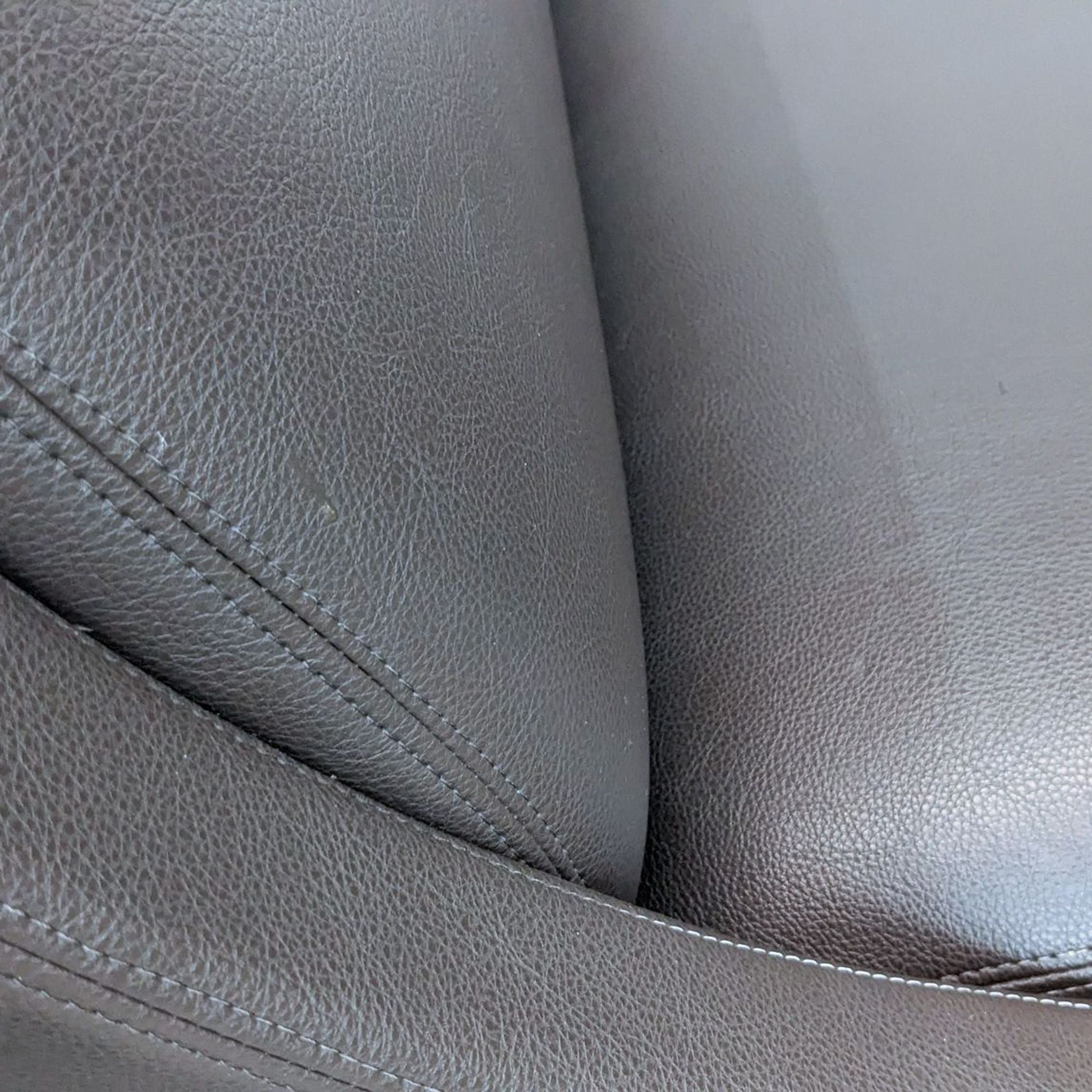 Close-up of the clean line brown leather texture and stitching on a Reperch loveseat.