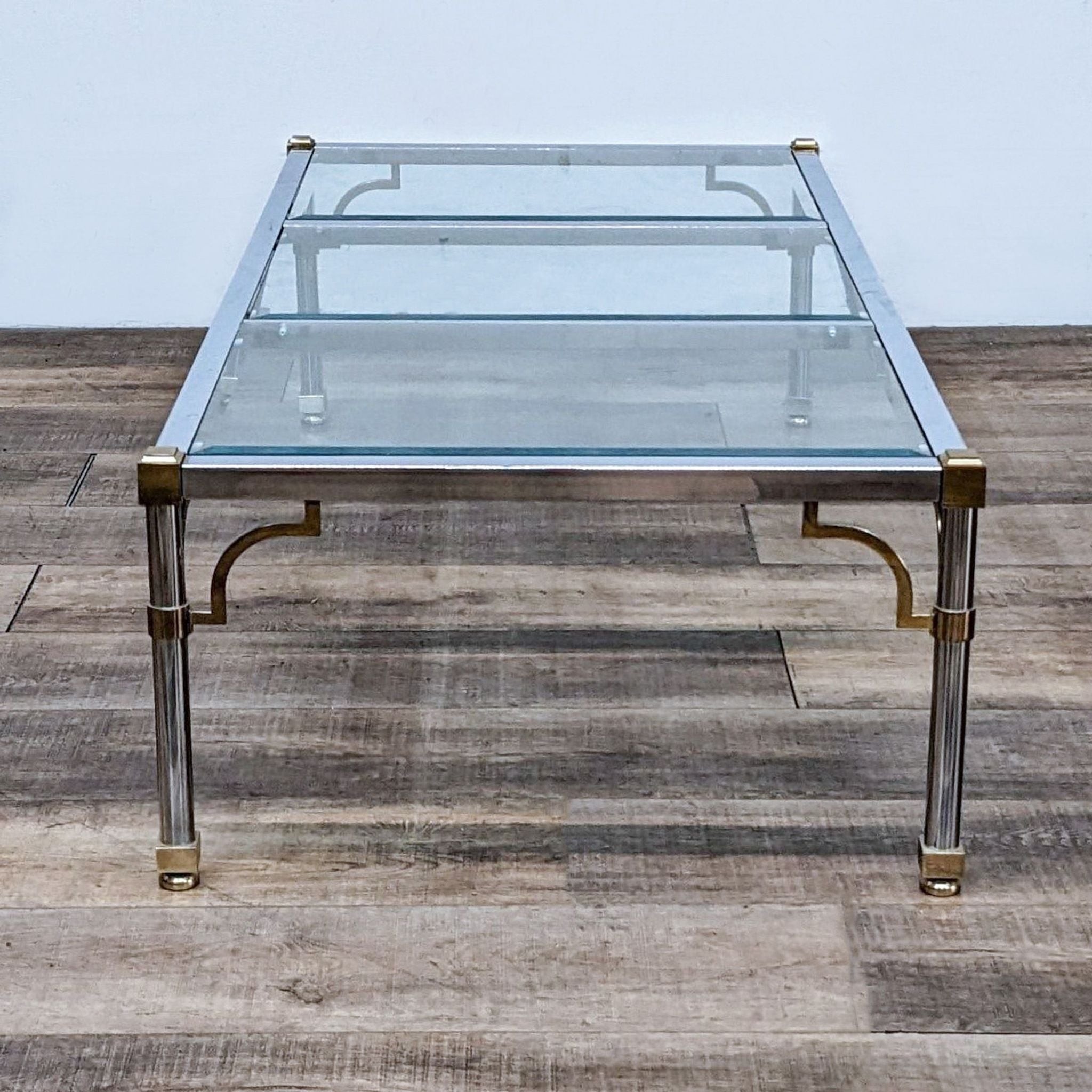 Reperch brand coffee table featuring a clear glass surface with metallic golden detailing on leg connectors.