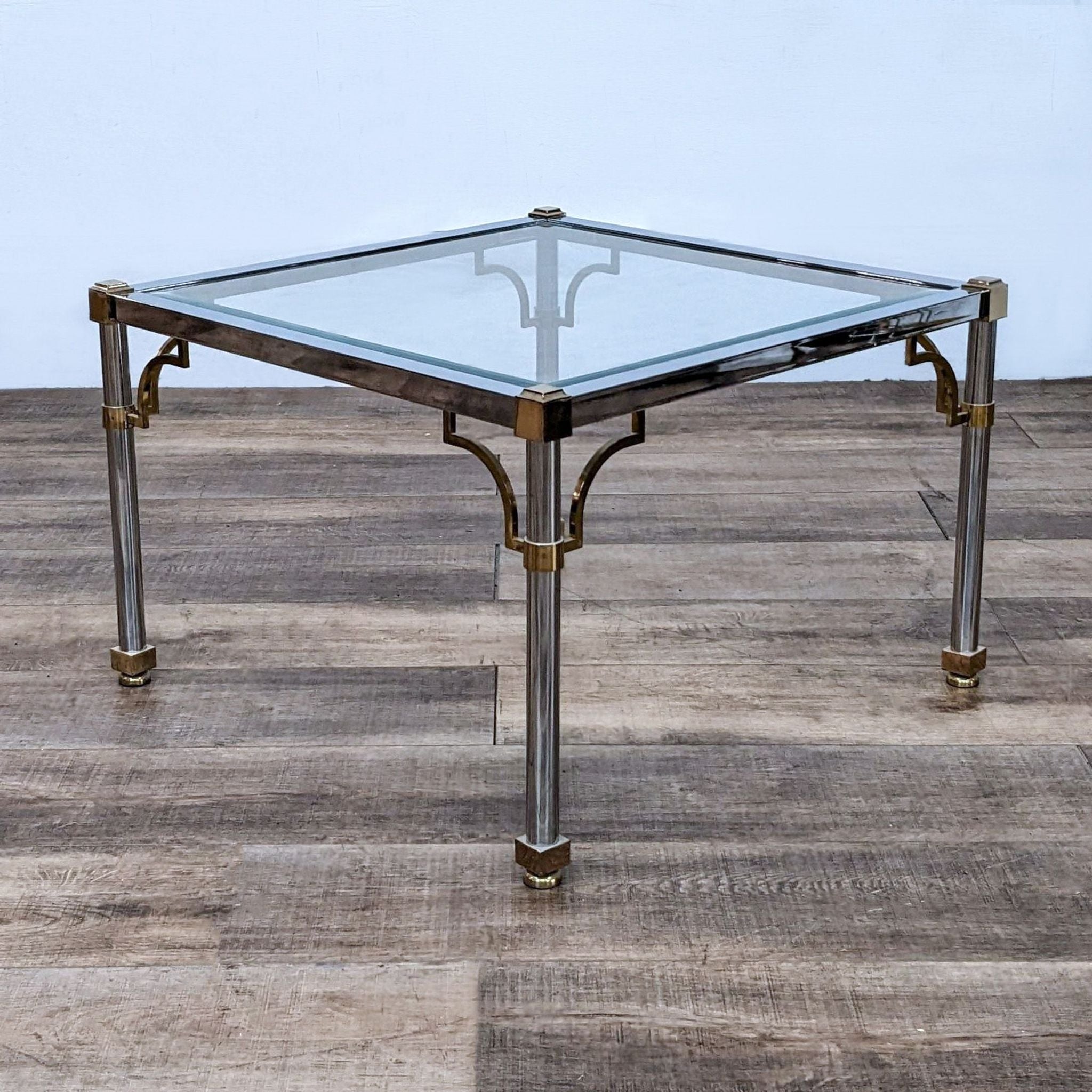 Modern glass Reperch end table with sleek silver frame and elegant golden details, set against a wooden background.
