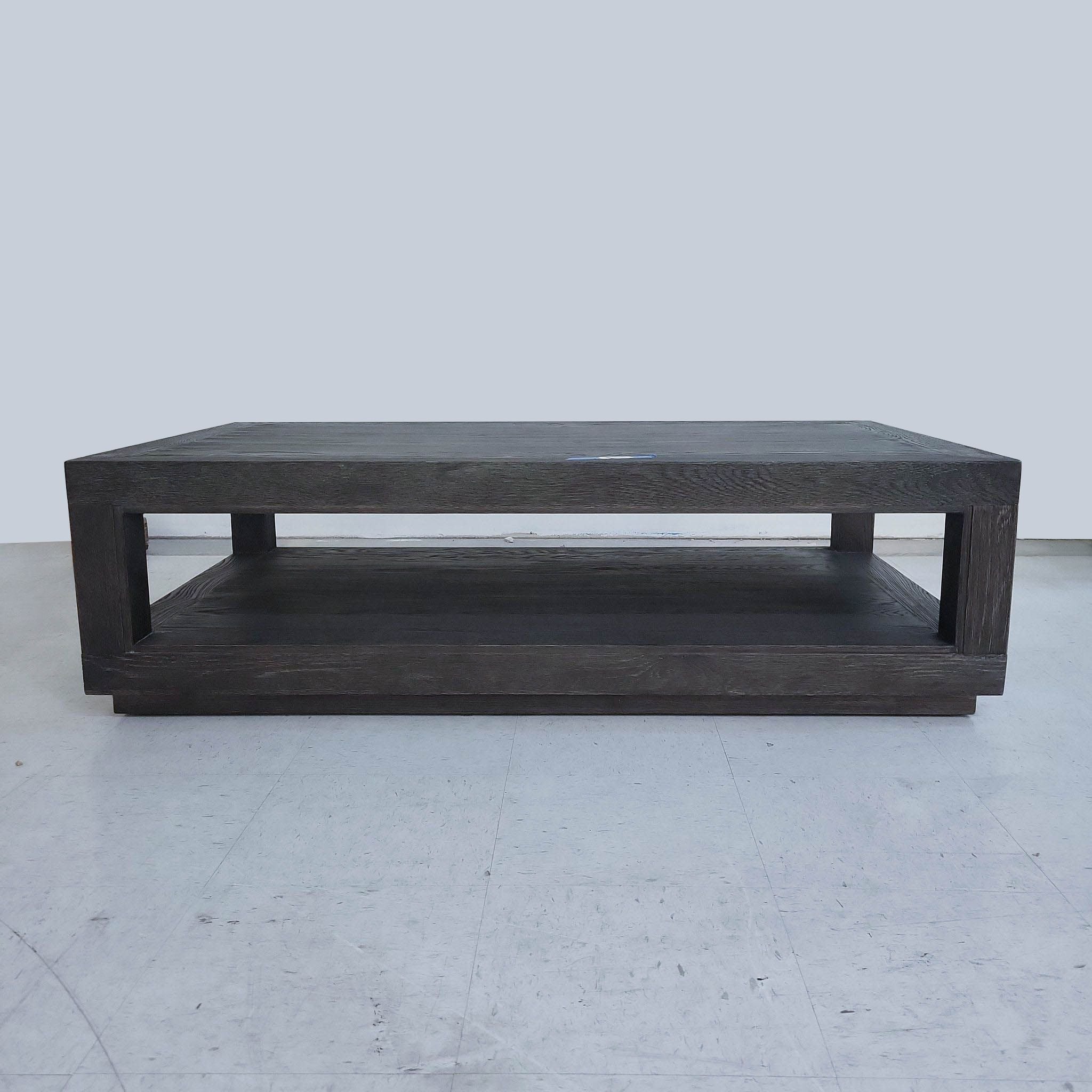 Restoration Hardware coffee table, dark wood, with lower shelf, in a frontal view on a light floor.