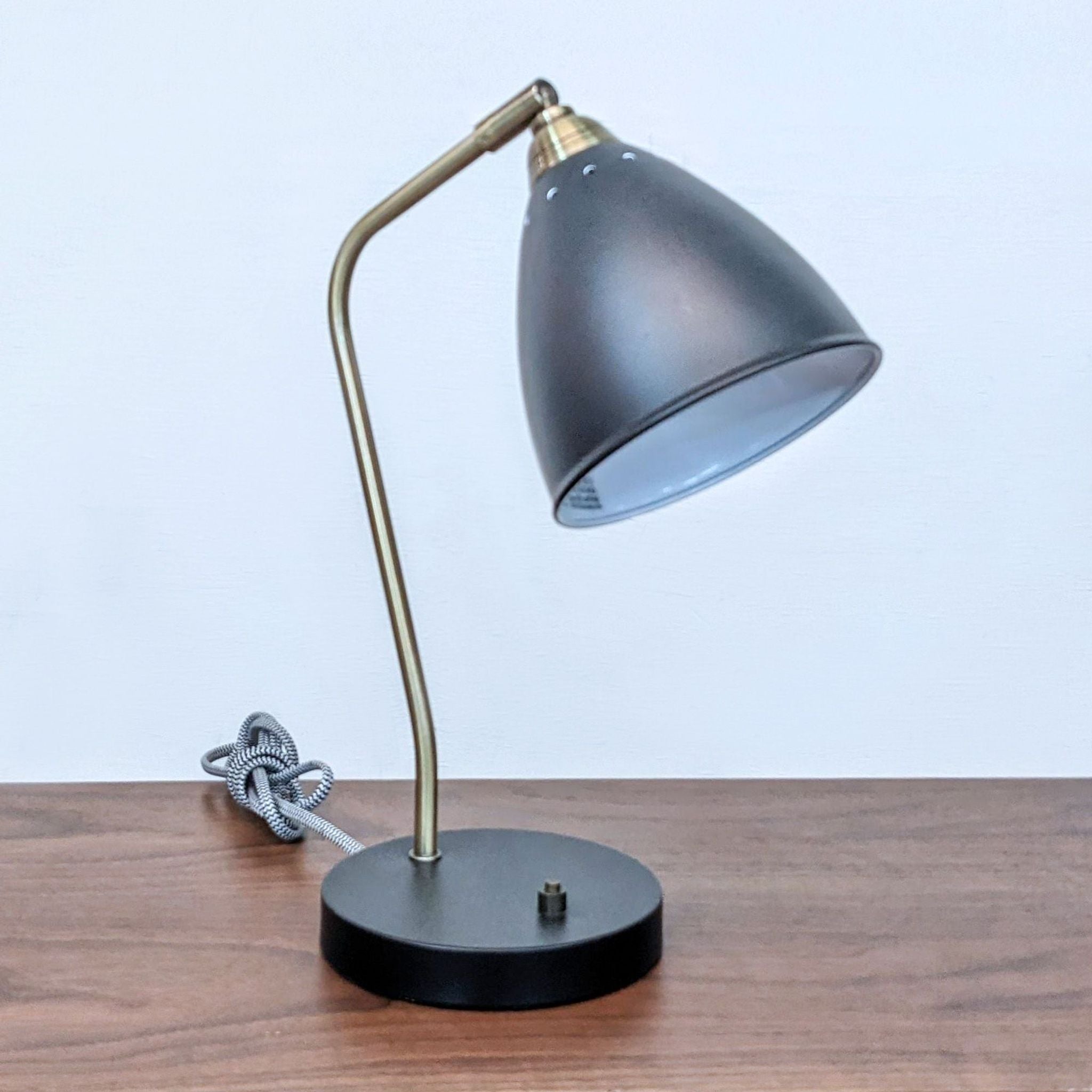 Reperch brand desk lamp with an adjustable gold arm and gray shade, placed on a wooden surface.