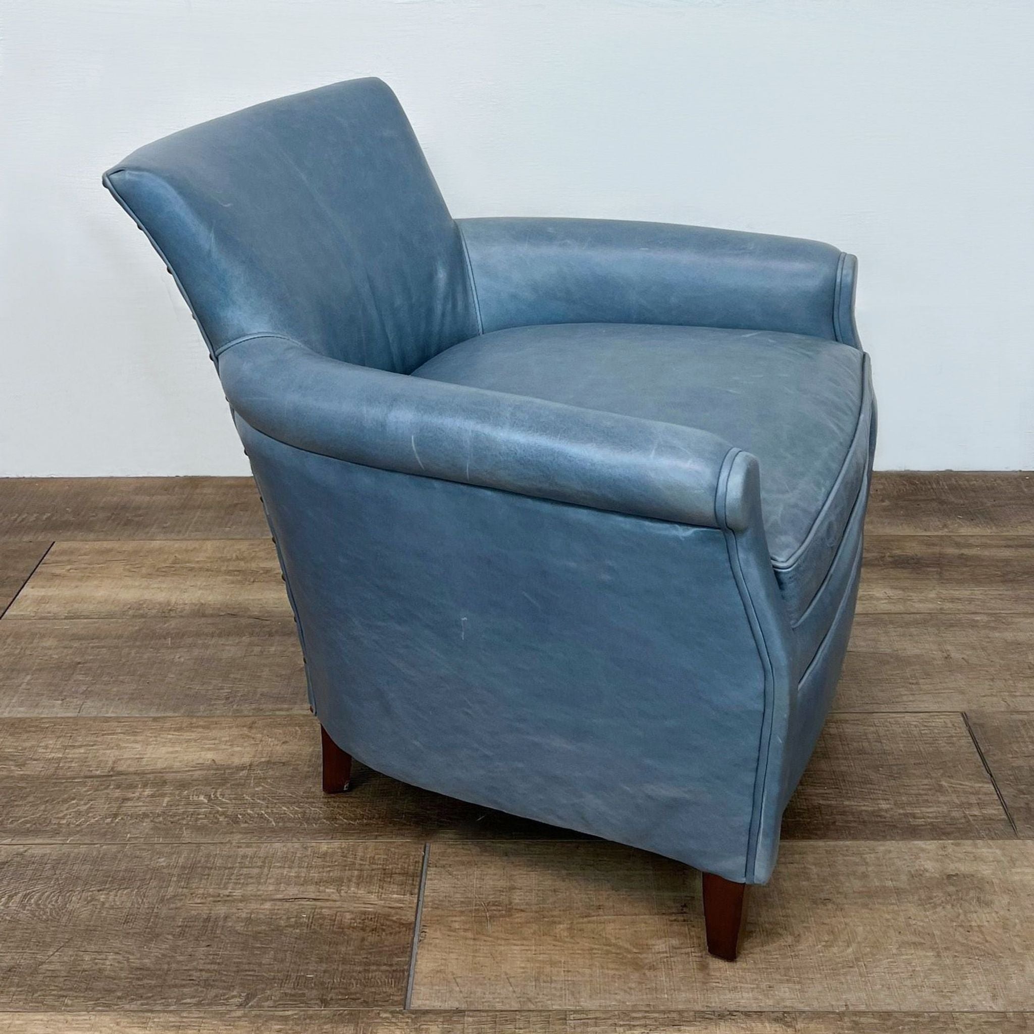 Moore and Giles 33 Original leather lounge chair in blue, showcasing the side profile and wooden legs on a hardwood floor.