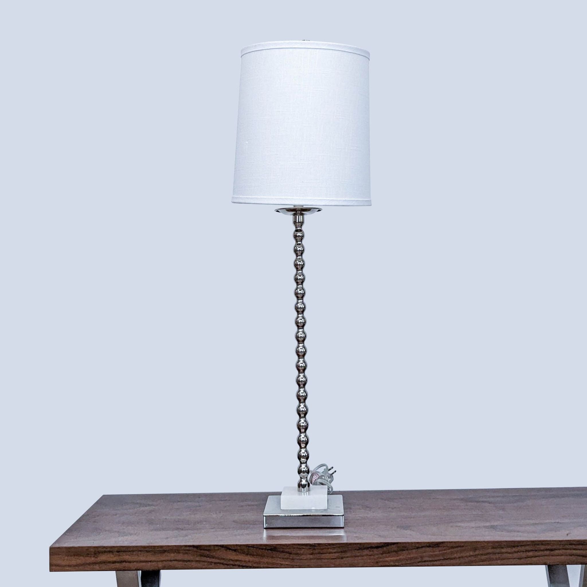 Reperch branded tabletop lamp with a white shade and spherical metal stem on a wooden surface.