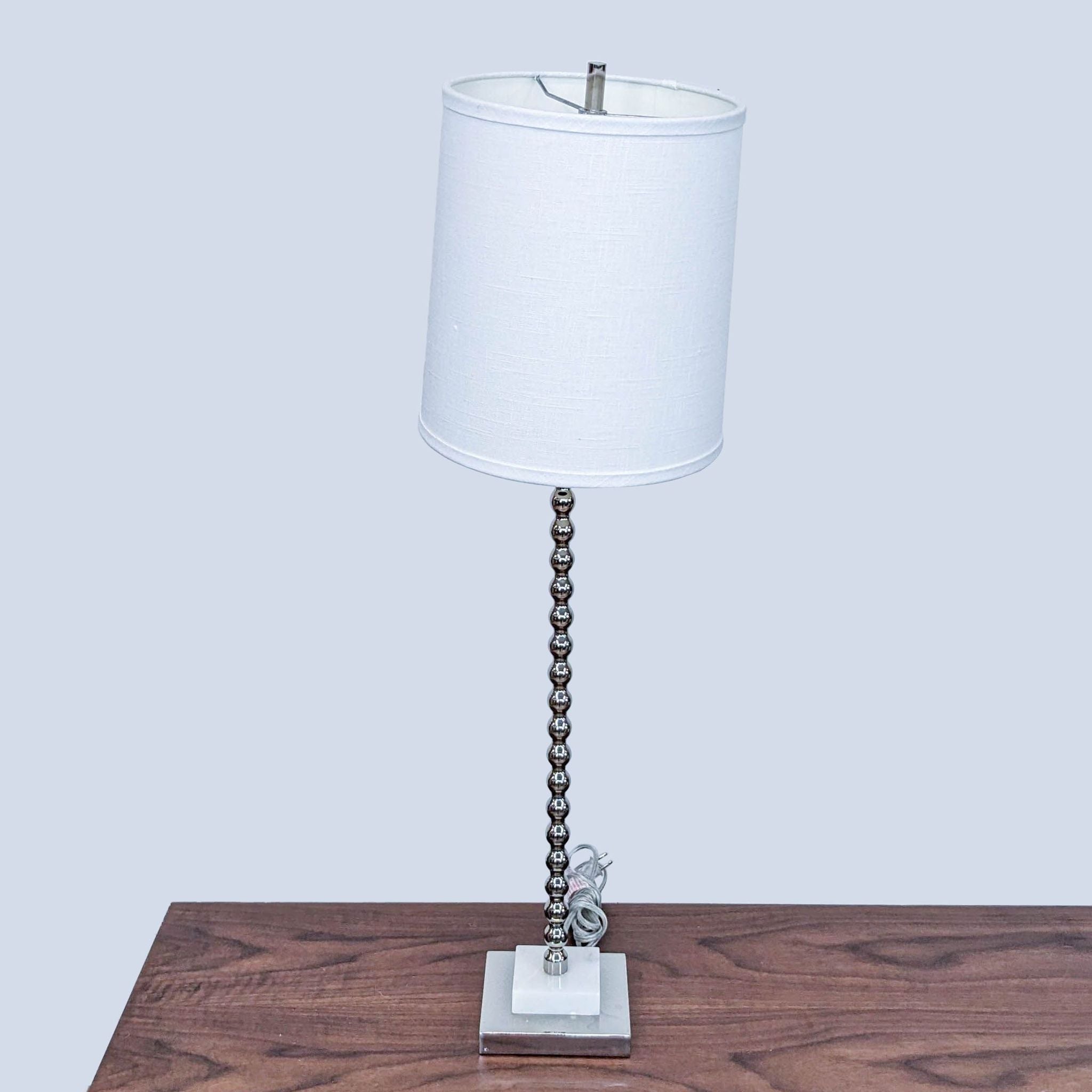 Elegant Reperch lighting, featuring a white cylindrical lampshade and a decorative metal base on a table.