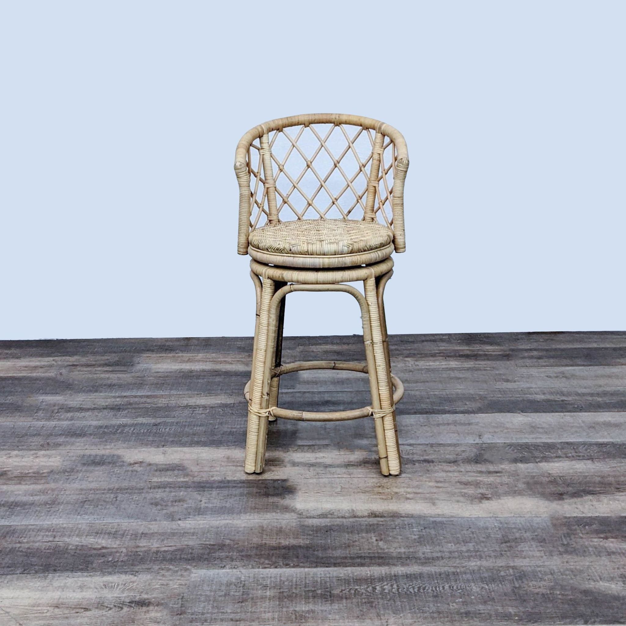 Serena and Lily Avalon Rattan Swivel Stool with open weave back on wooden floor.