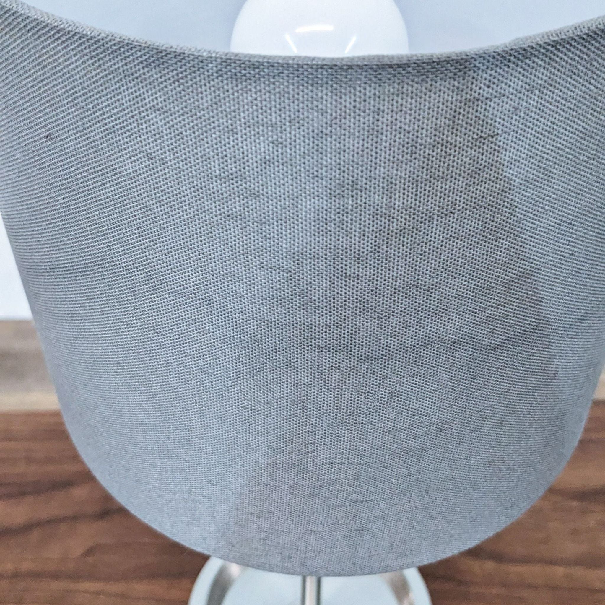Close-up of a Reperch brand lamp with a gray fabric shade and white base on a wooden floor.