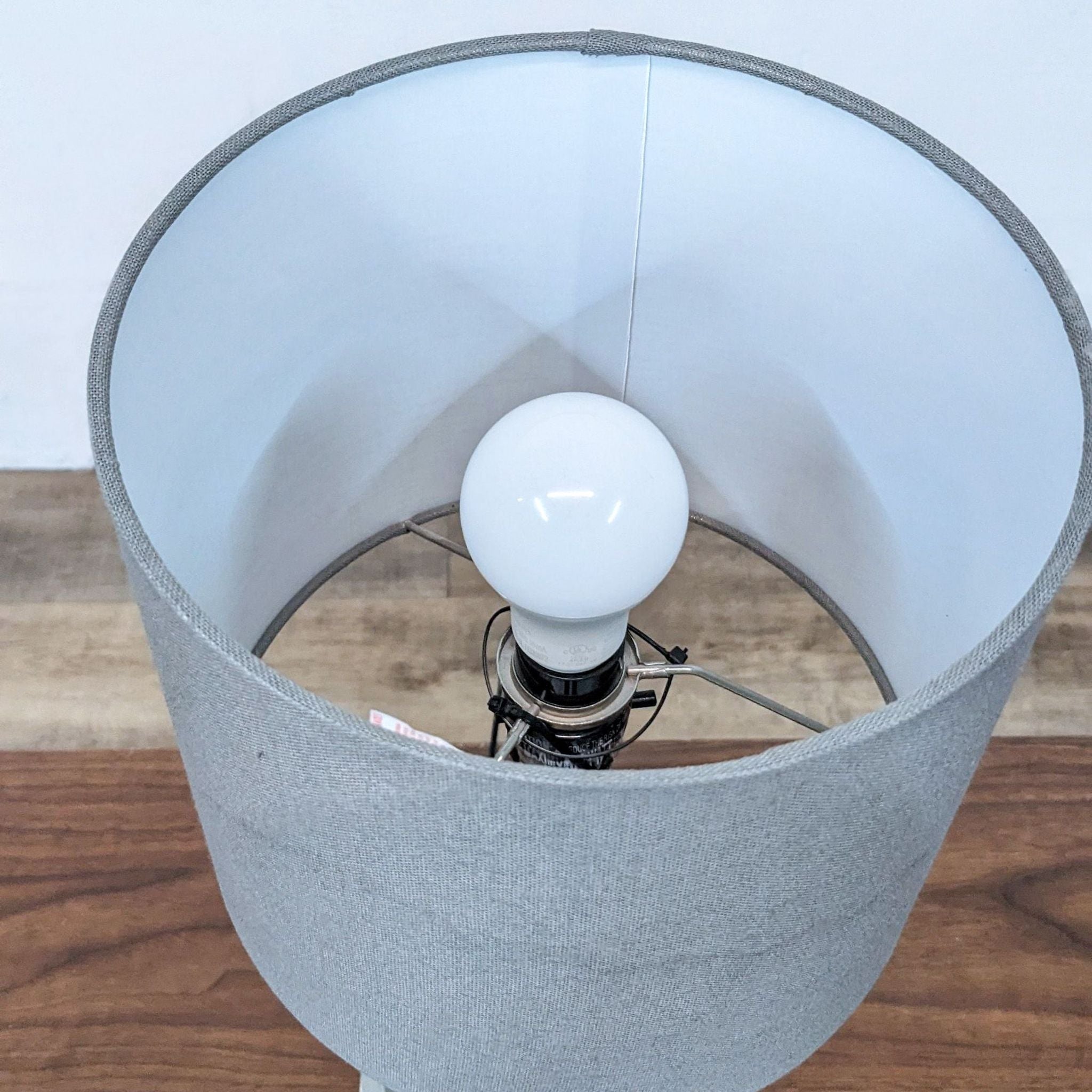 Top view of a Reperch lamp showing a lit bulb and inside of the grey lampshade.