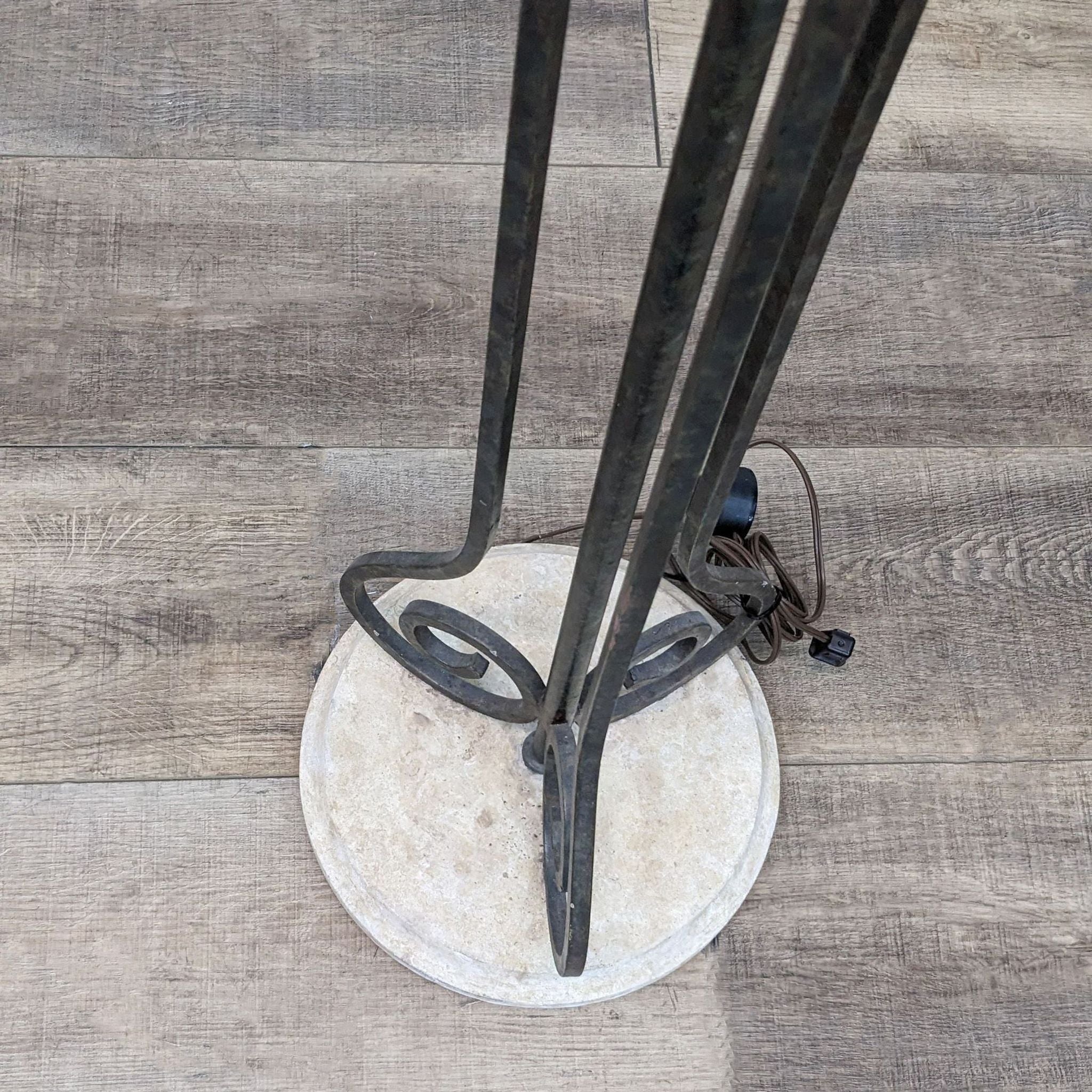 Top-down view of a Reperch brand floor lamp base with twisted metal design on wooden floor.