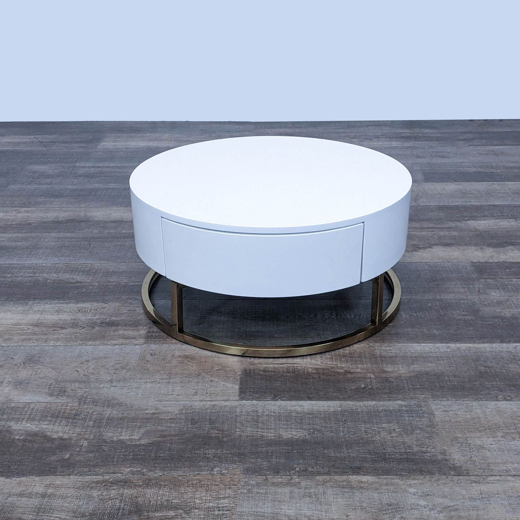 Alt text 1: Round Reperch coffee table with a white top and a metal base, on a wooden floor.