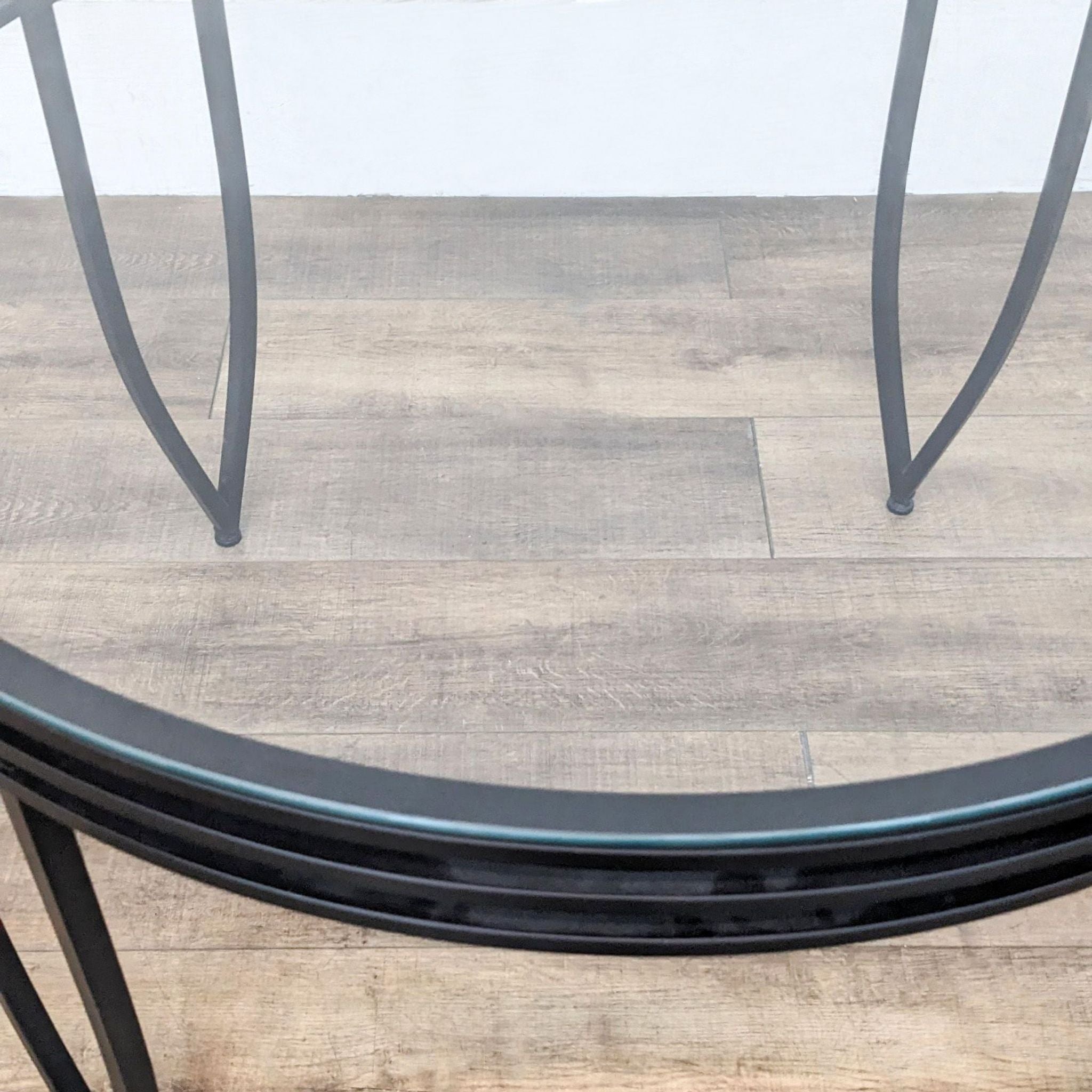 Reperch brand dining table with a metal base and round tempered glass top on a wooden floor.