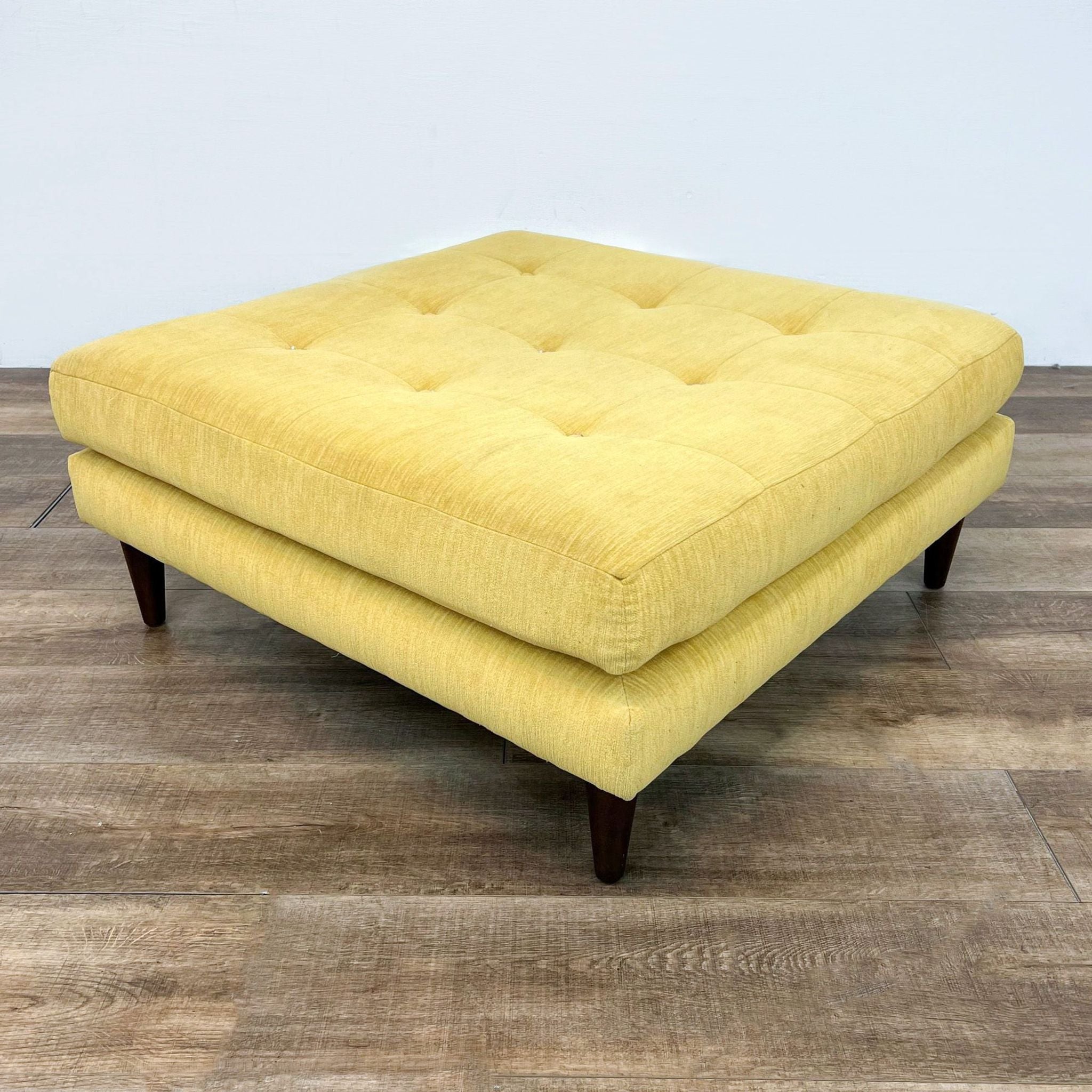 Joybird large square yellow tufted ottoman with tapered wooden feet.