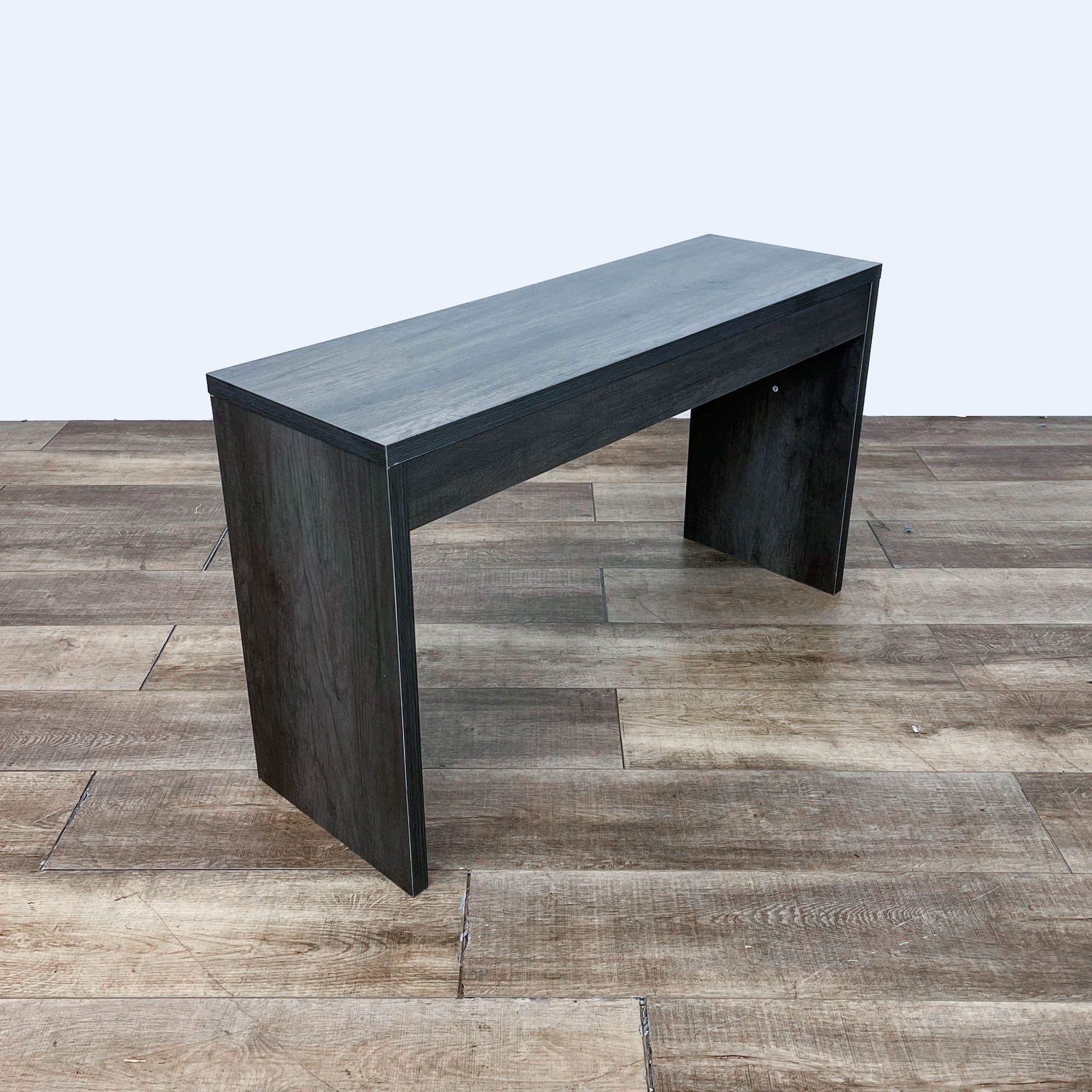 Angled view of a modern Reperch console table with a dark finish, highlighting the simplicity of its form and structure.