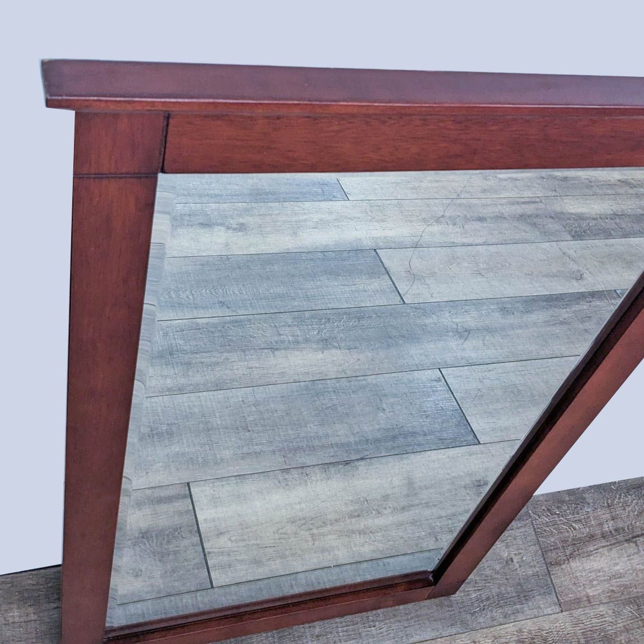 Close-up of Reperch wooden mirror frame corner showing detail of the wood and floor reflection.