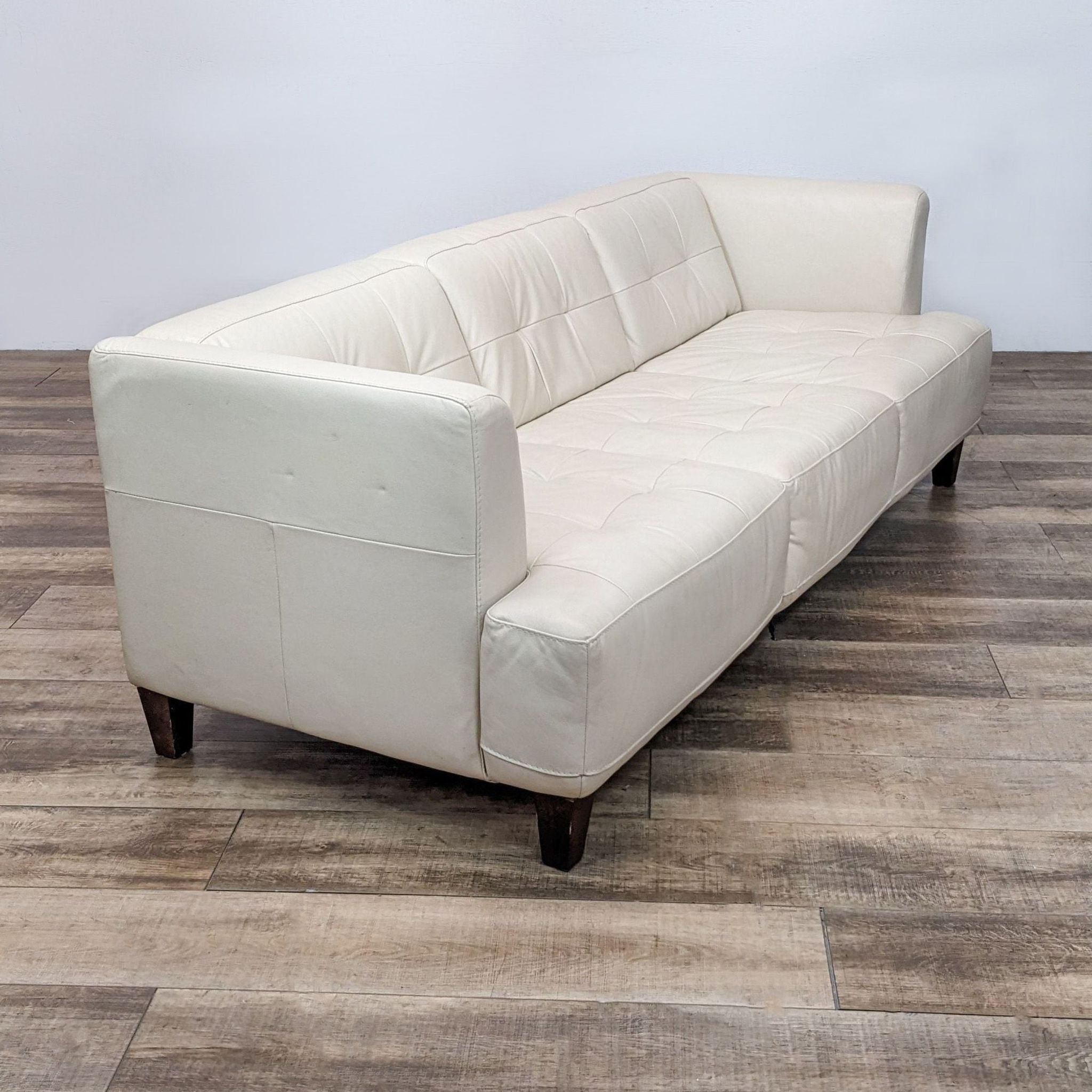 Angle view of Chateau d'Ax Italian 3-seat tufted leather sofa with dark finish legs and shelter arms.