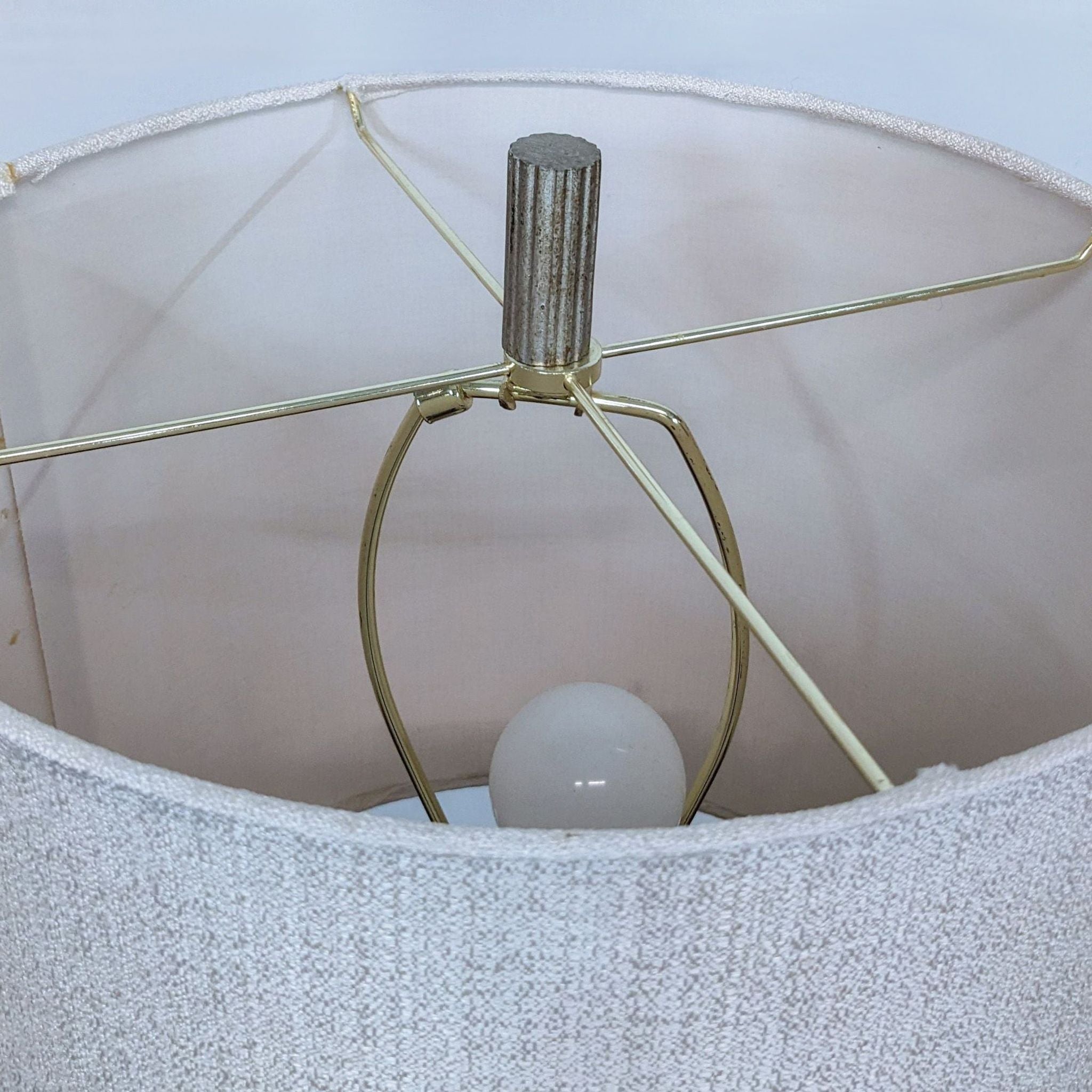 Close-up of a Reperch table lamp's metal structure and bulb under the white fabric shade, showing design details.