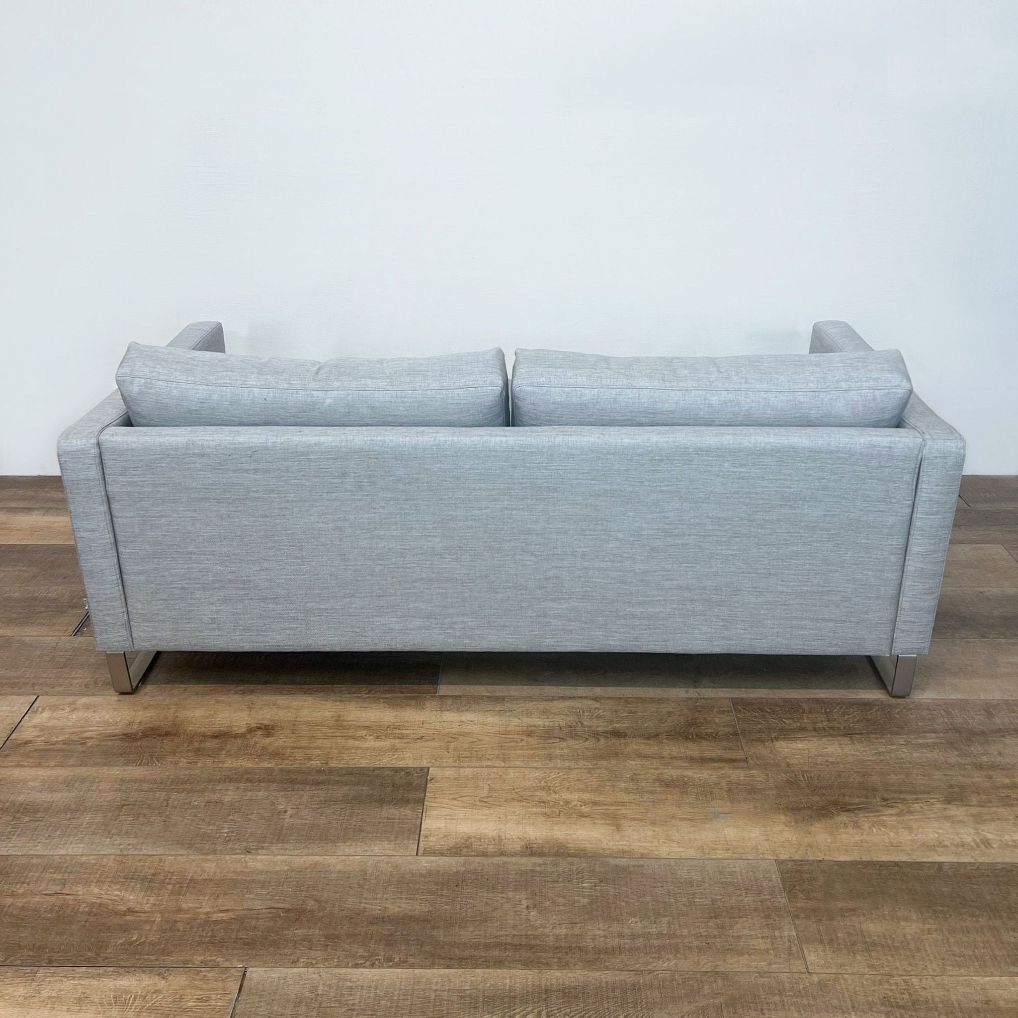 BoConcept Danish designer 3-seat gray sofa with clean lines, narrow arms, and metal frame legs on wooden floor.