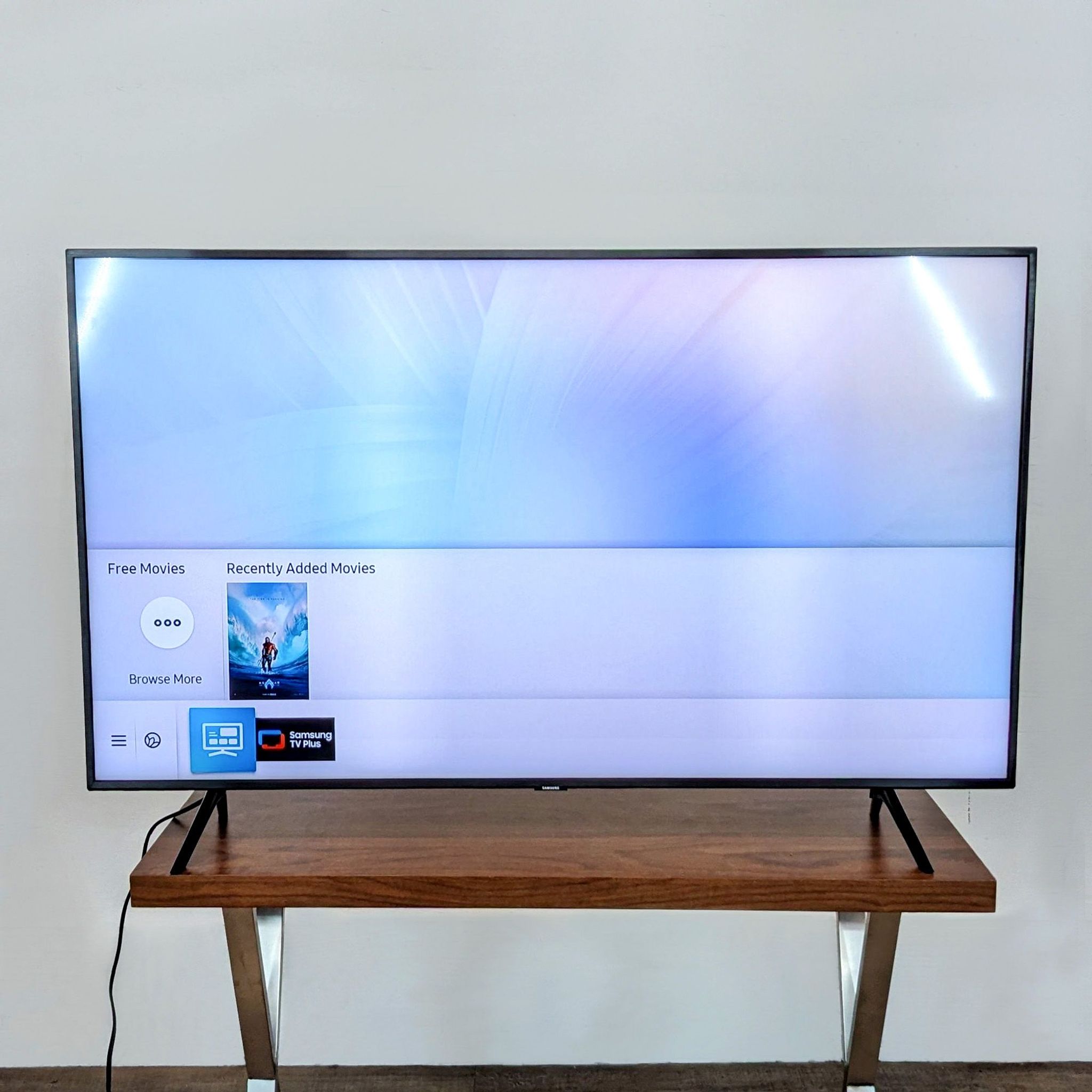Side view of a Samsung flat-screen TV showing its slim profile and stand on a wooden table.