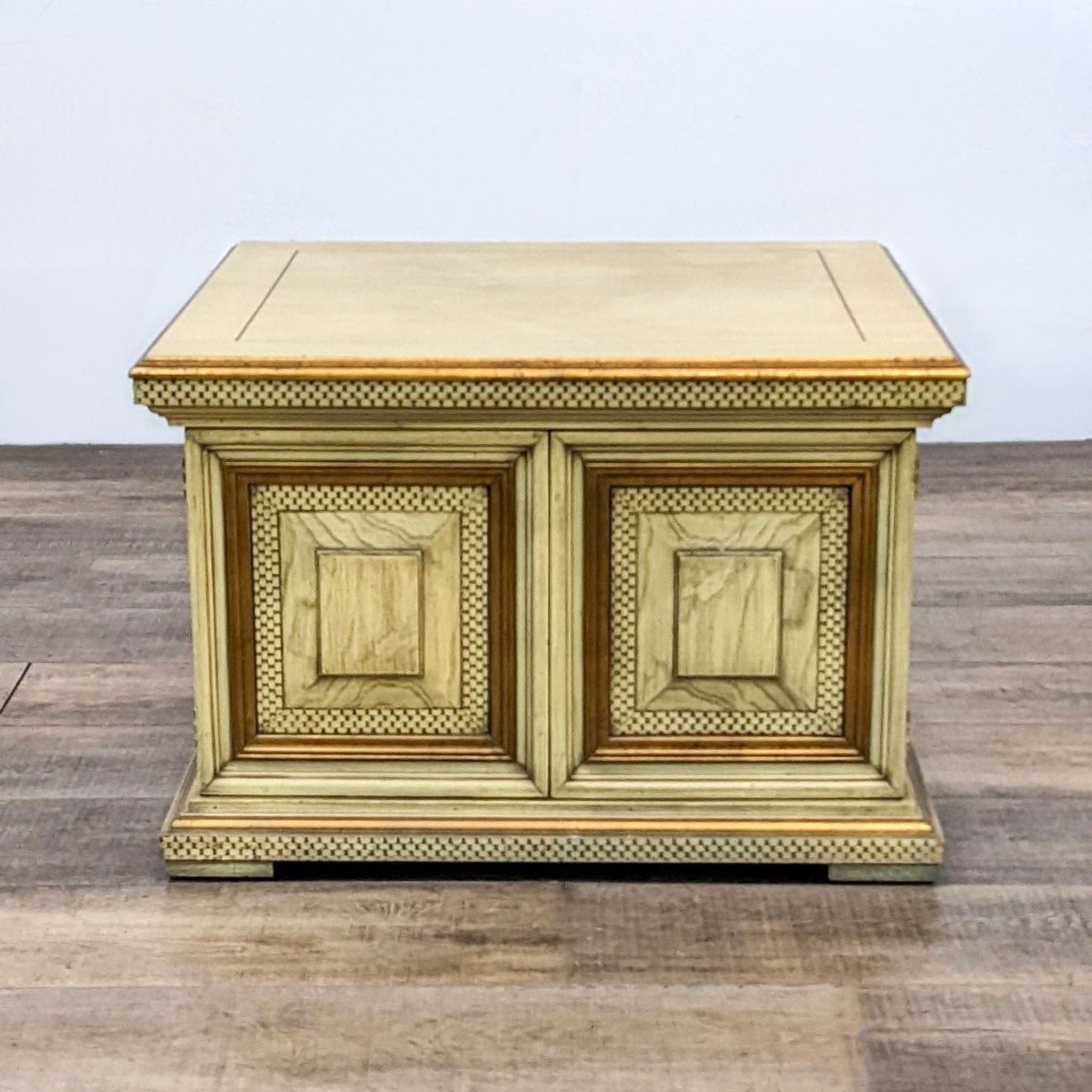 Reperch brand end table with intricate beaded detailing and two closed panel doors, set against a wood floor.