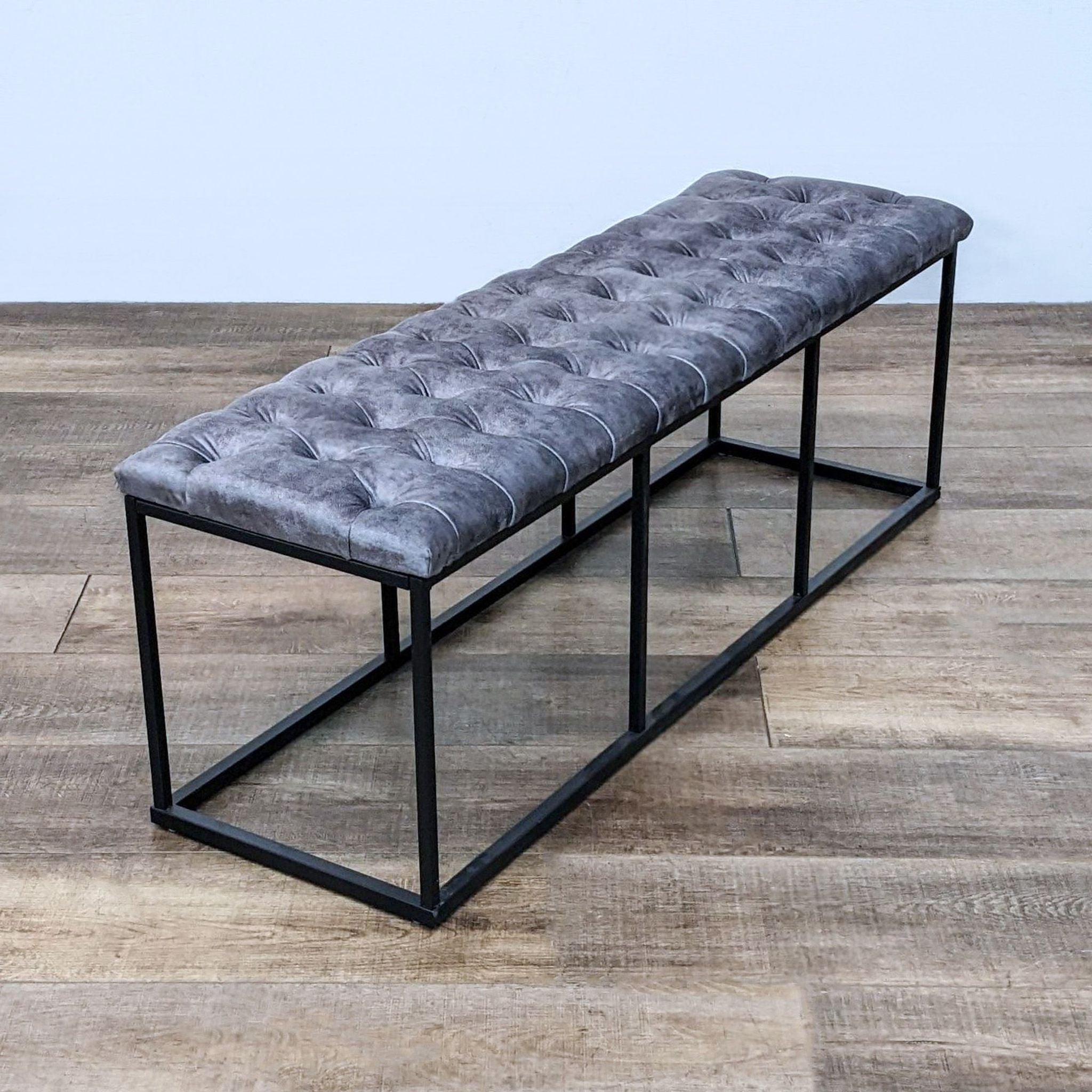 Tufted leather bench by Reperch, with dark metal frame, 52 inches, showcased on a wooden floor.