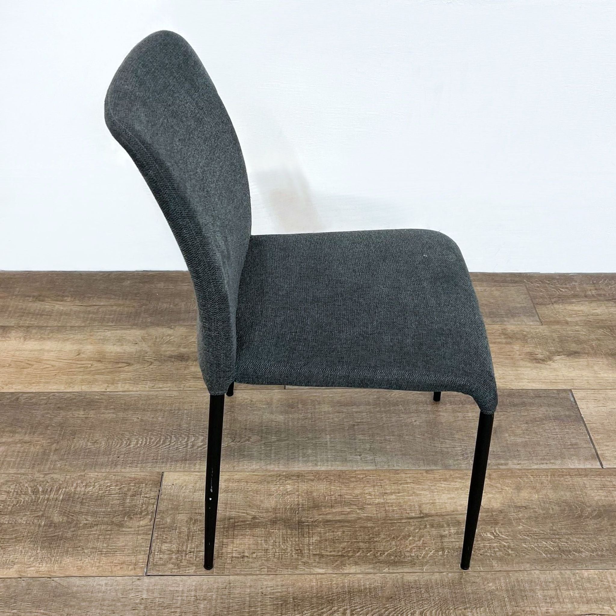 Charcoal upholstered Reperch dining chair with curved backrest and sleek tapered legs, angled side view.