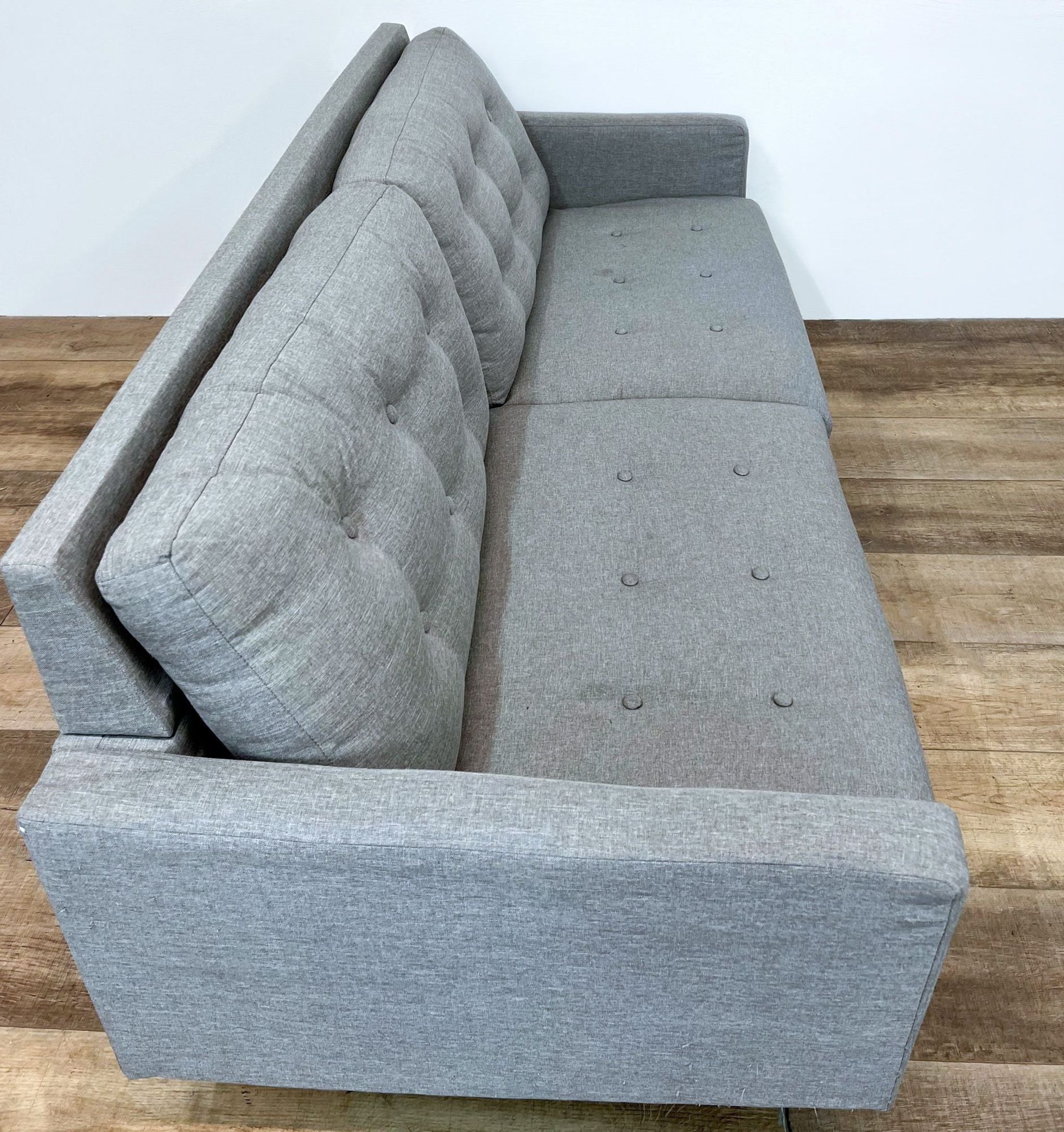 Gray Aeon Furniture 3-seat compact sofa with tufted backrest and tapered feet on wooden floor.