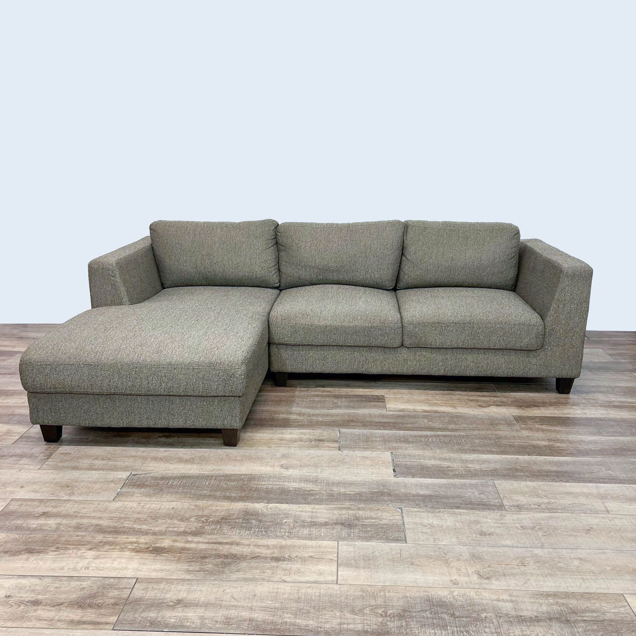 Modern Reperch clean-lined sectional sofa with chaise and dark wooden legs, arranged on a wooden floor.
