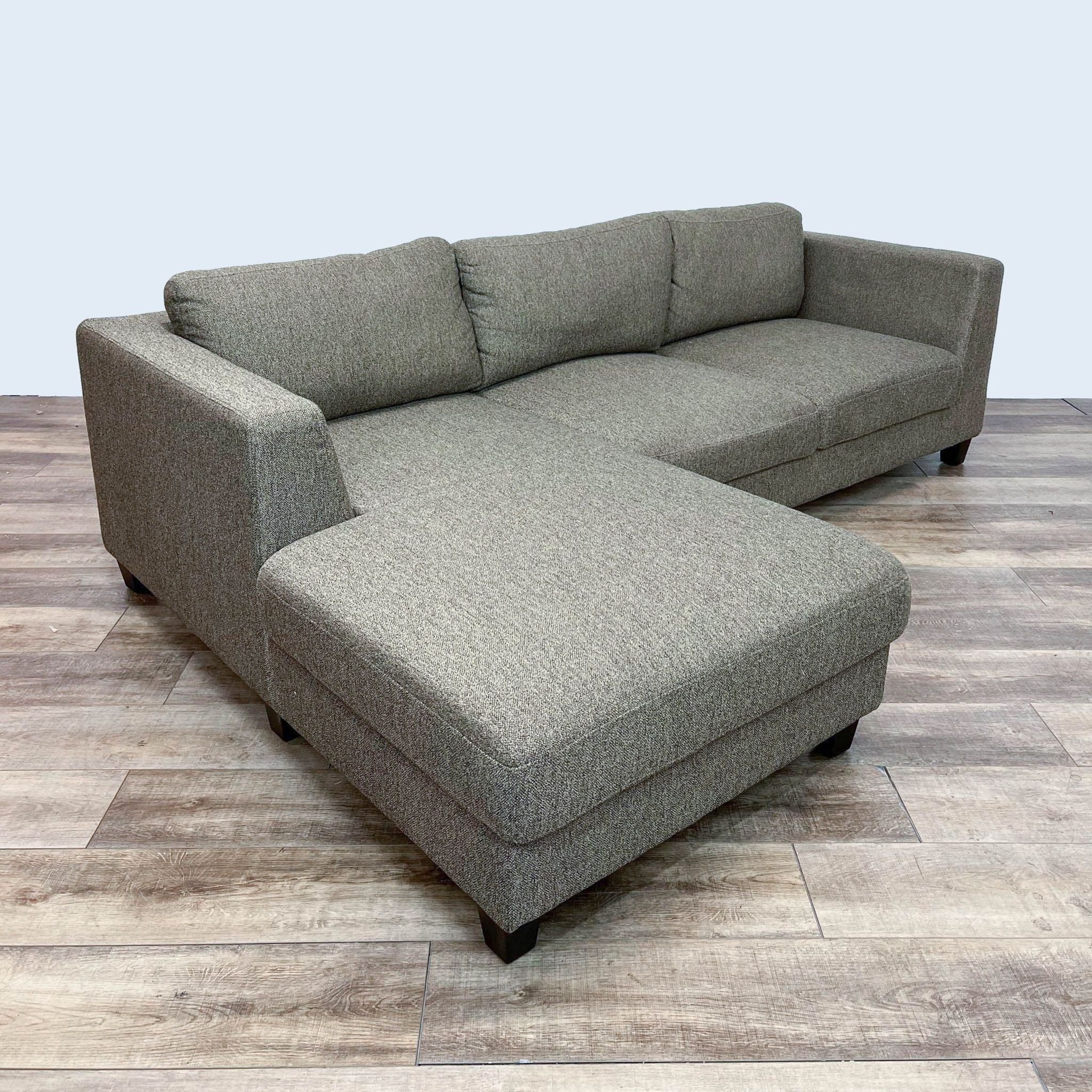 Reperch contemporary sectional with clean lines and dark wood finish feet on wooden floor.
