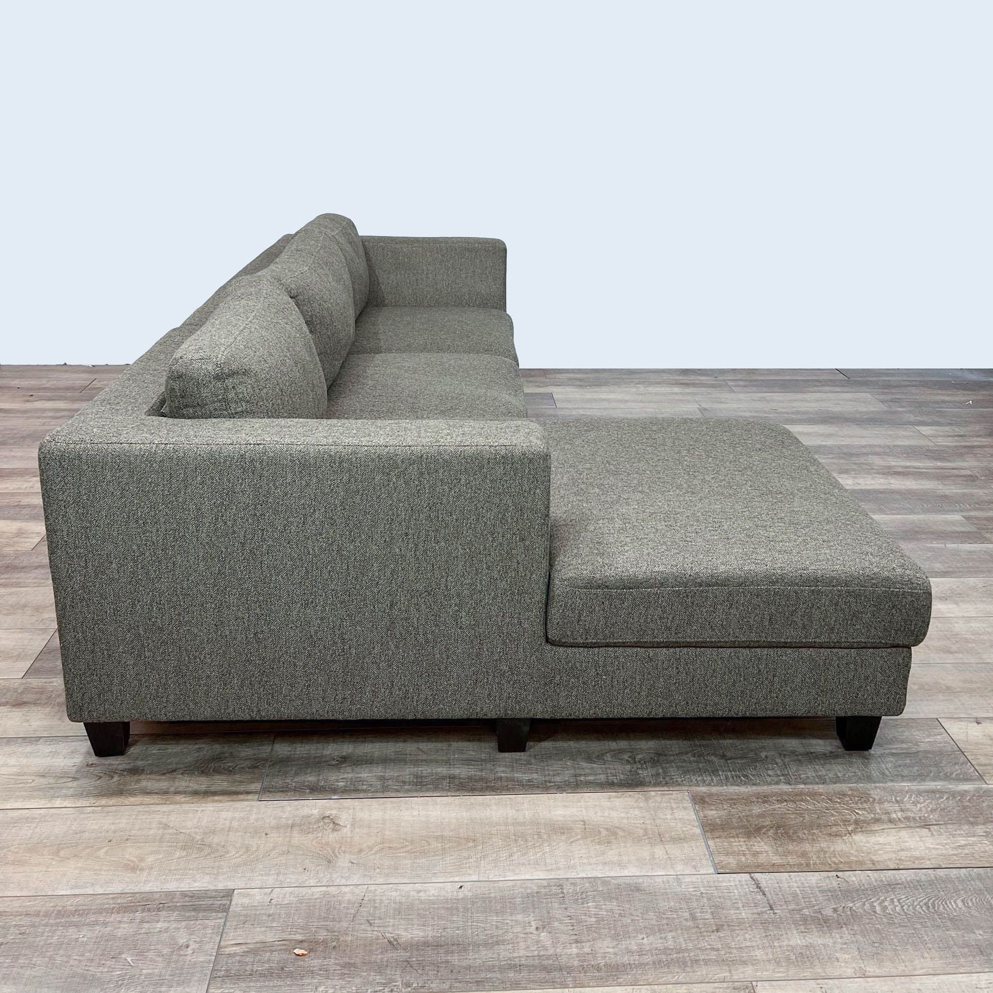 Reperch contemporary sectional sofa with clean lines and dark wooden feet on a wooden floor.