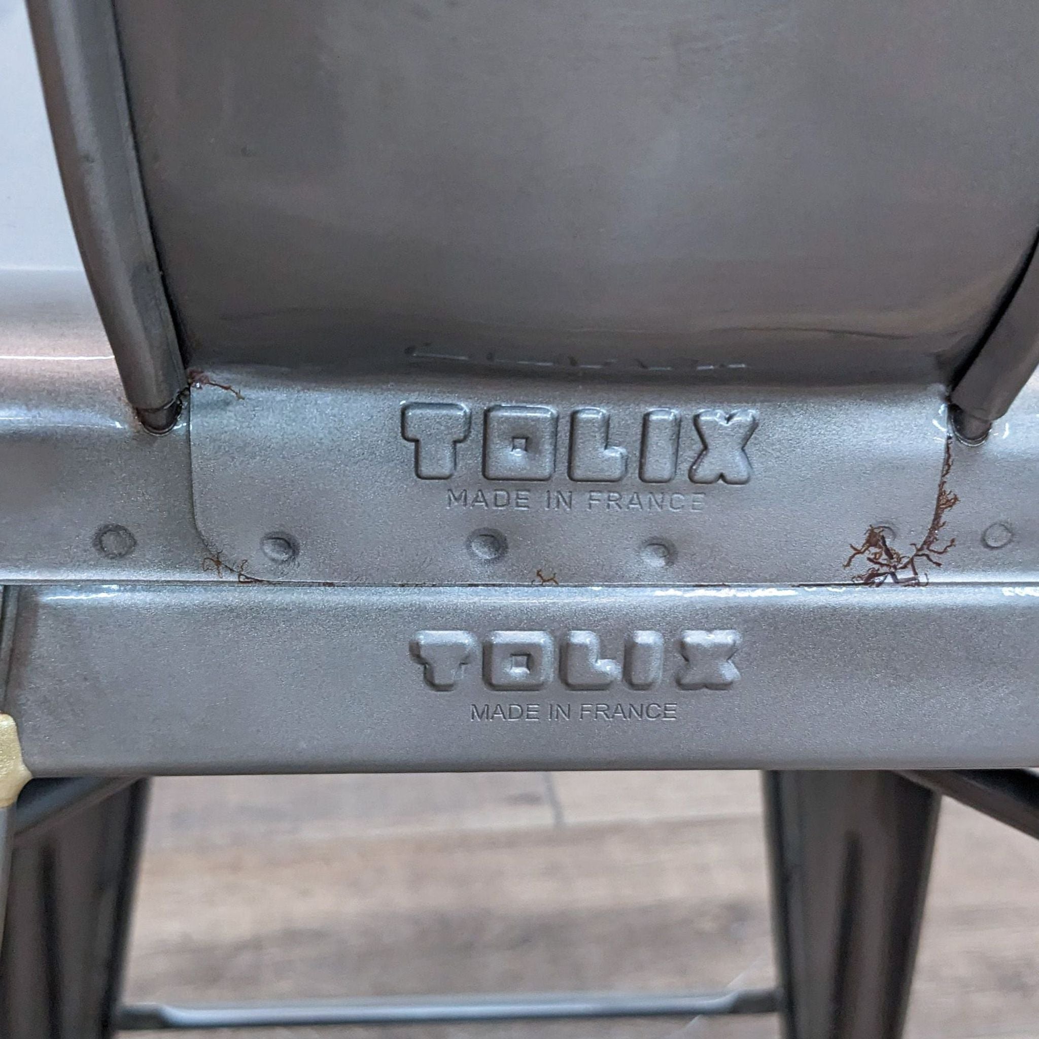Alt text 2: A close-up of the Tolix branding on the steel frame of a stool designed by Xacier Pauchard.