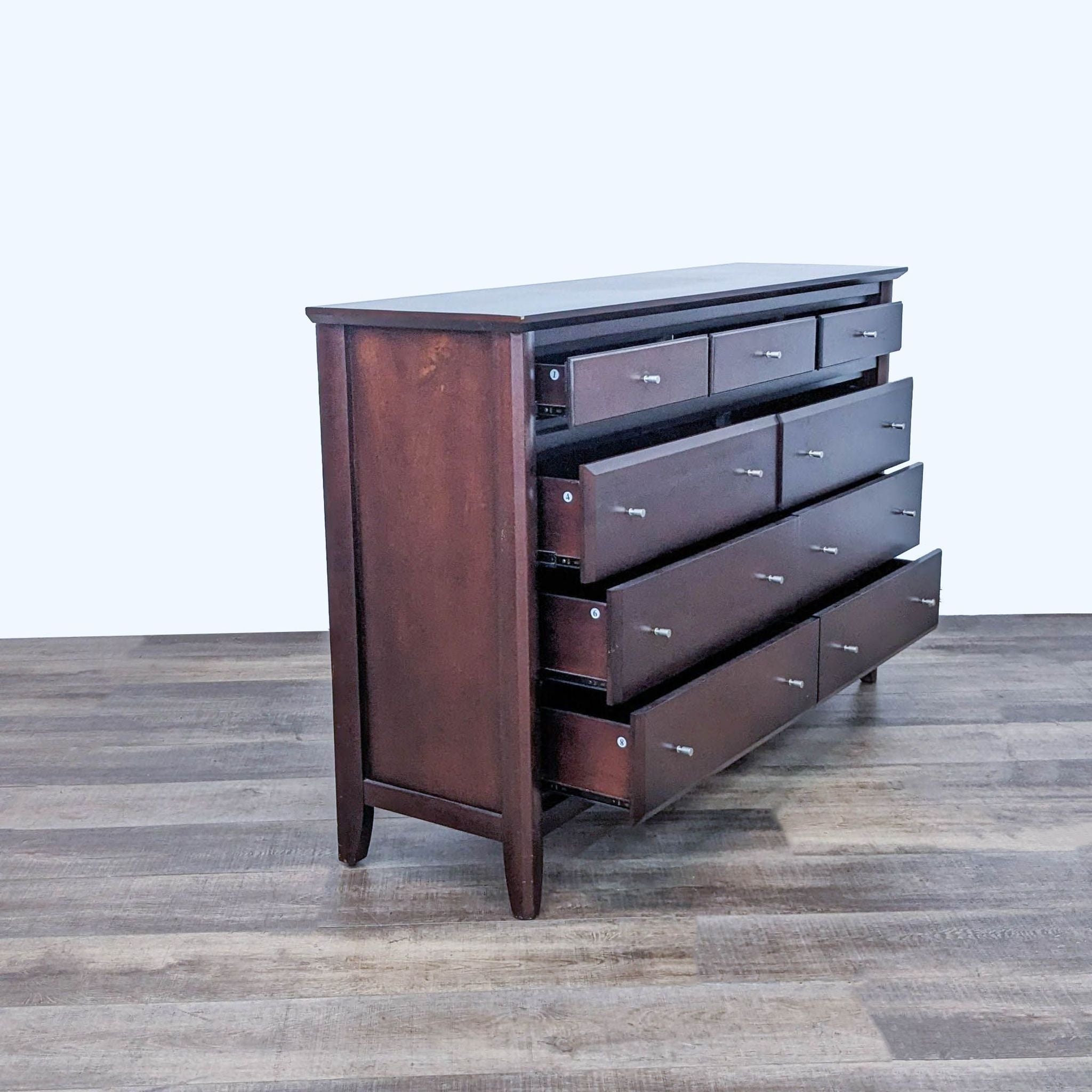 Front view of a Reperch walnut-finished dresser with three small and six large drawers, set on a wooden floor.