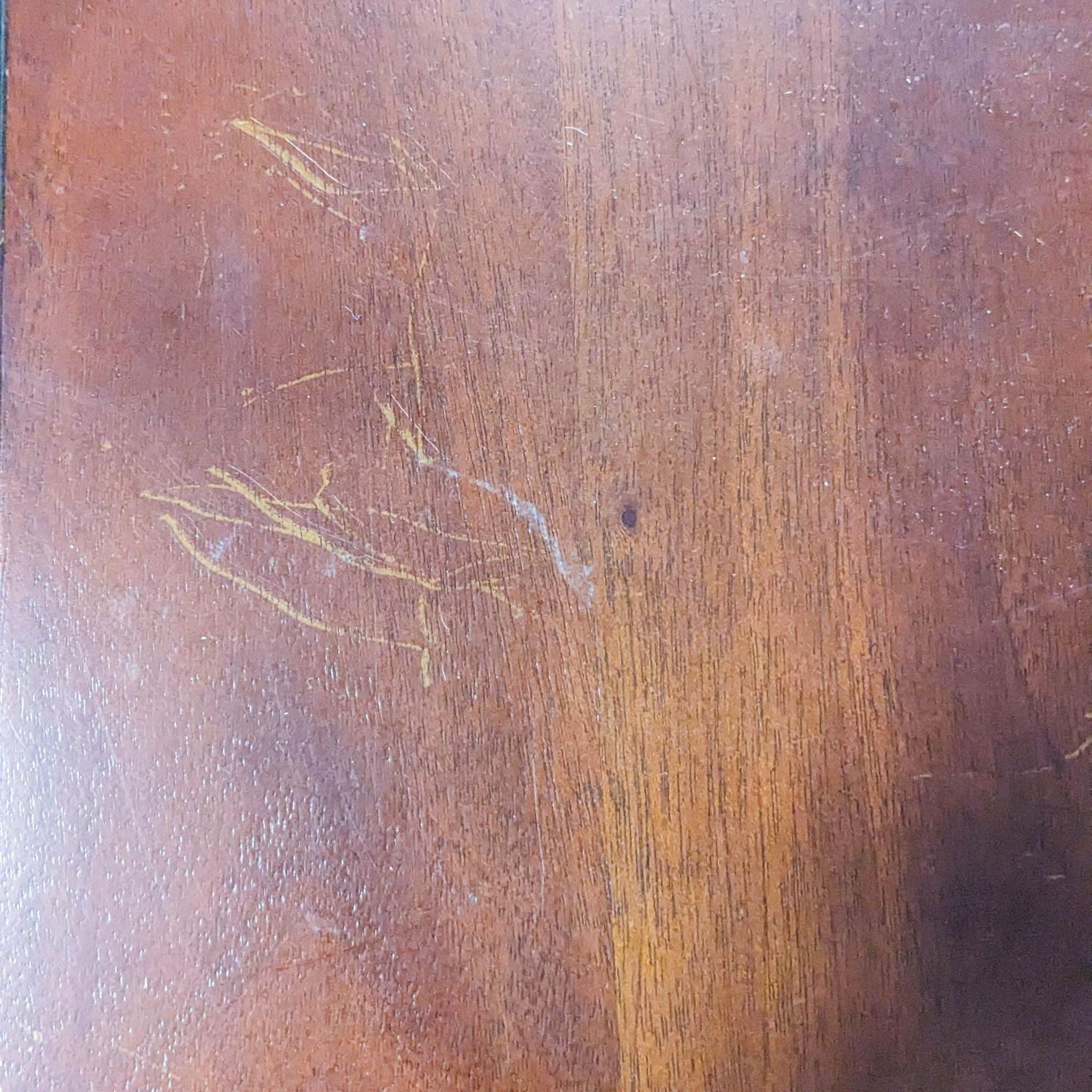 Close-up of a wooden surface showing scratches and wear, potentially part of a Pottery Barn furniture piece.