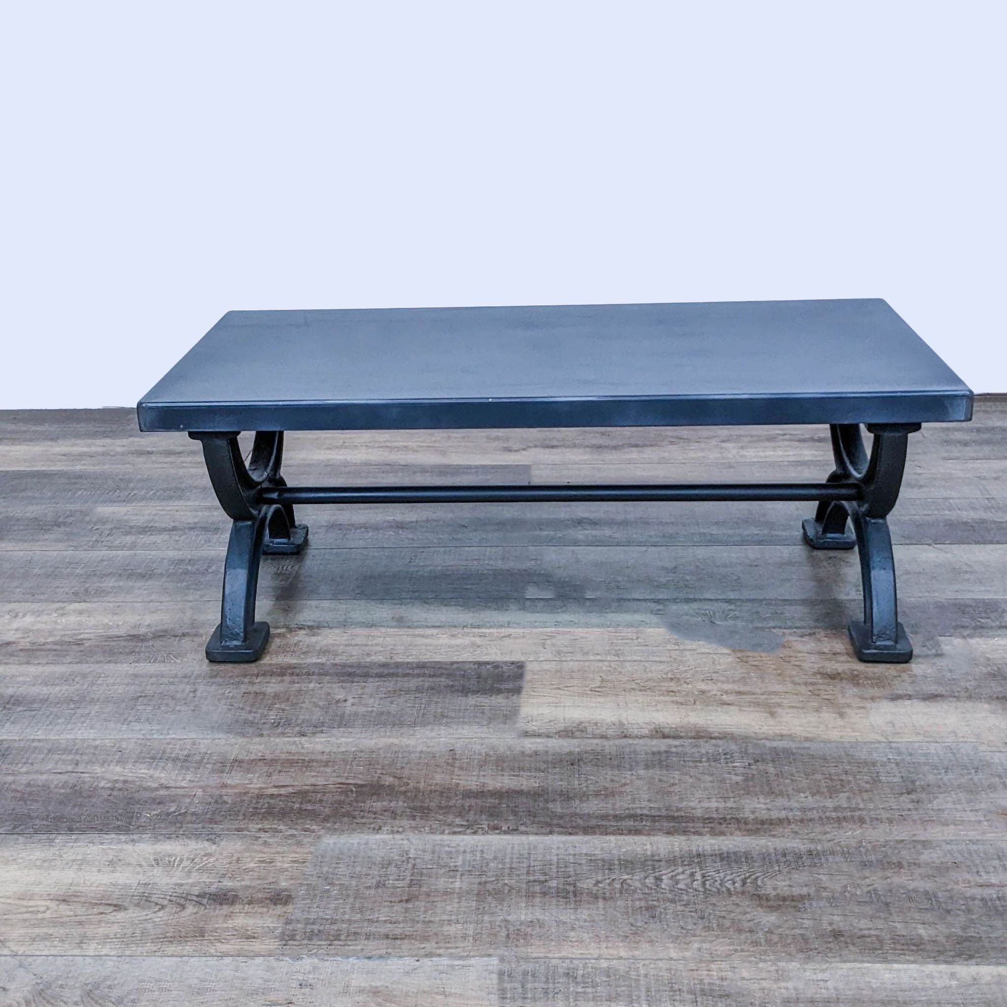 1940s-style Restoration Hardware coffee table crafted with iron legs in an X-form and a patinated metal top, embodying an industrial aesthetic.
