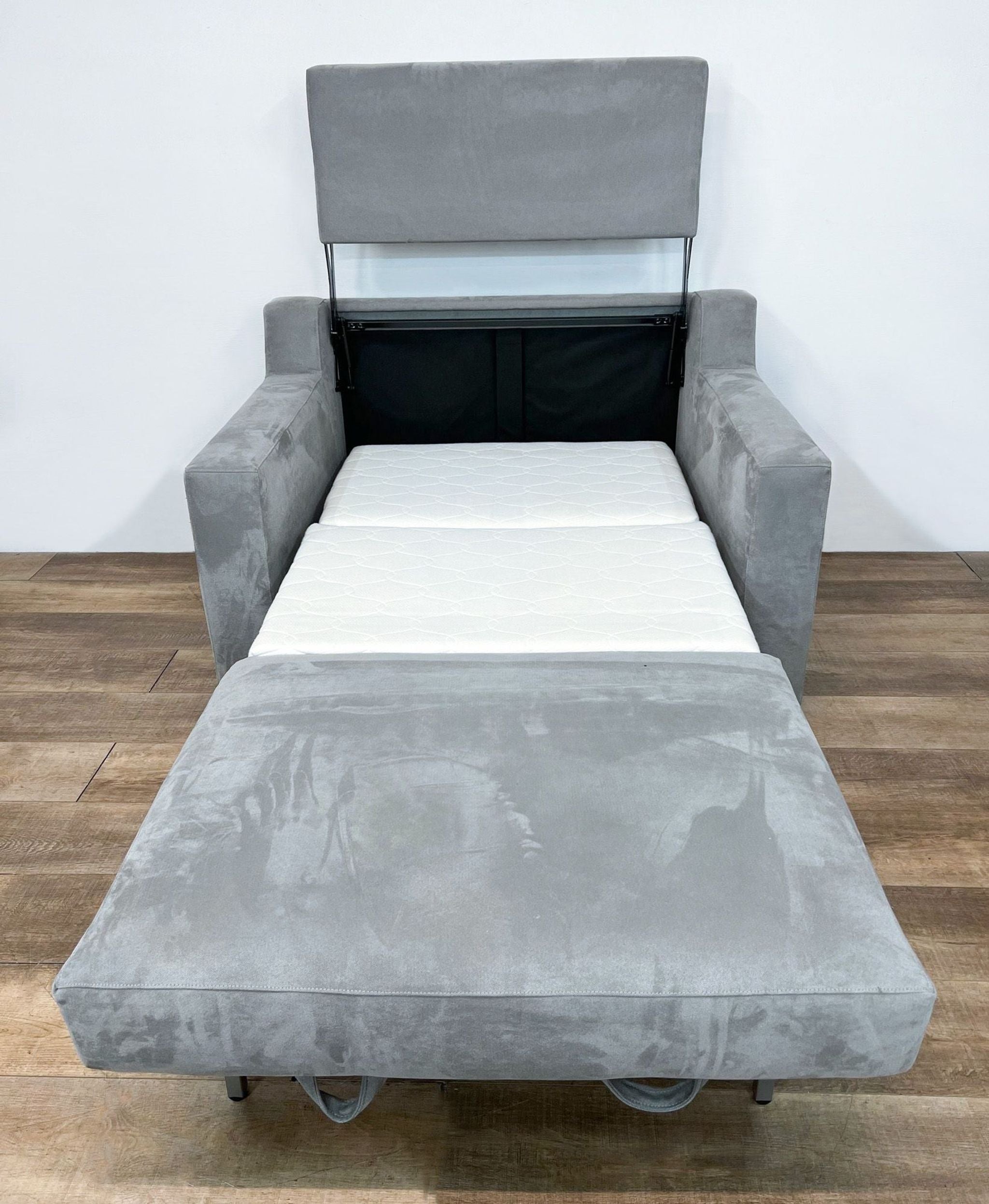 Crate & Barrel gray twin sleeper sofa open, showing fold-out memory foam mattress and adjustable headrest.
